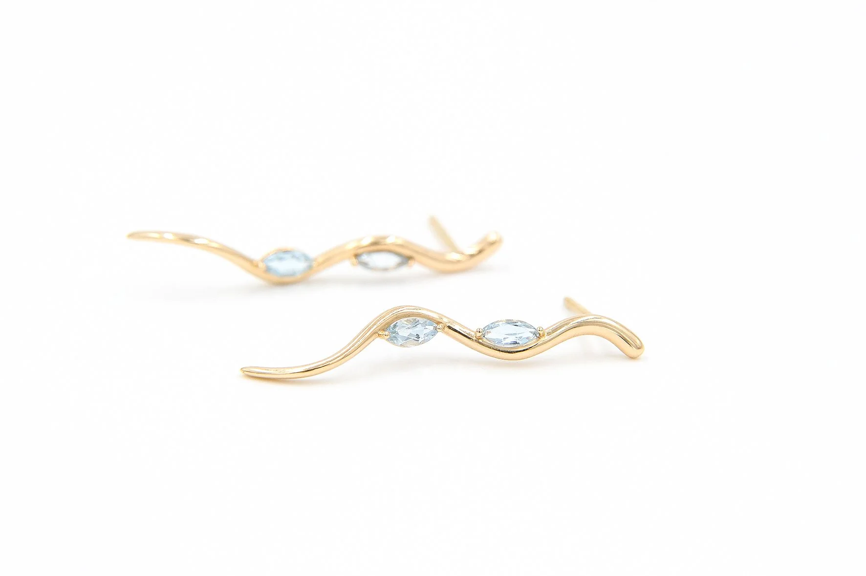 Gold earrings with wavy design and light blue gemstones on a white background.