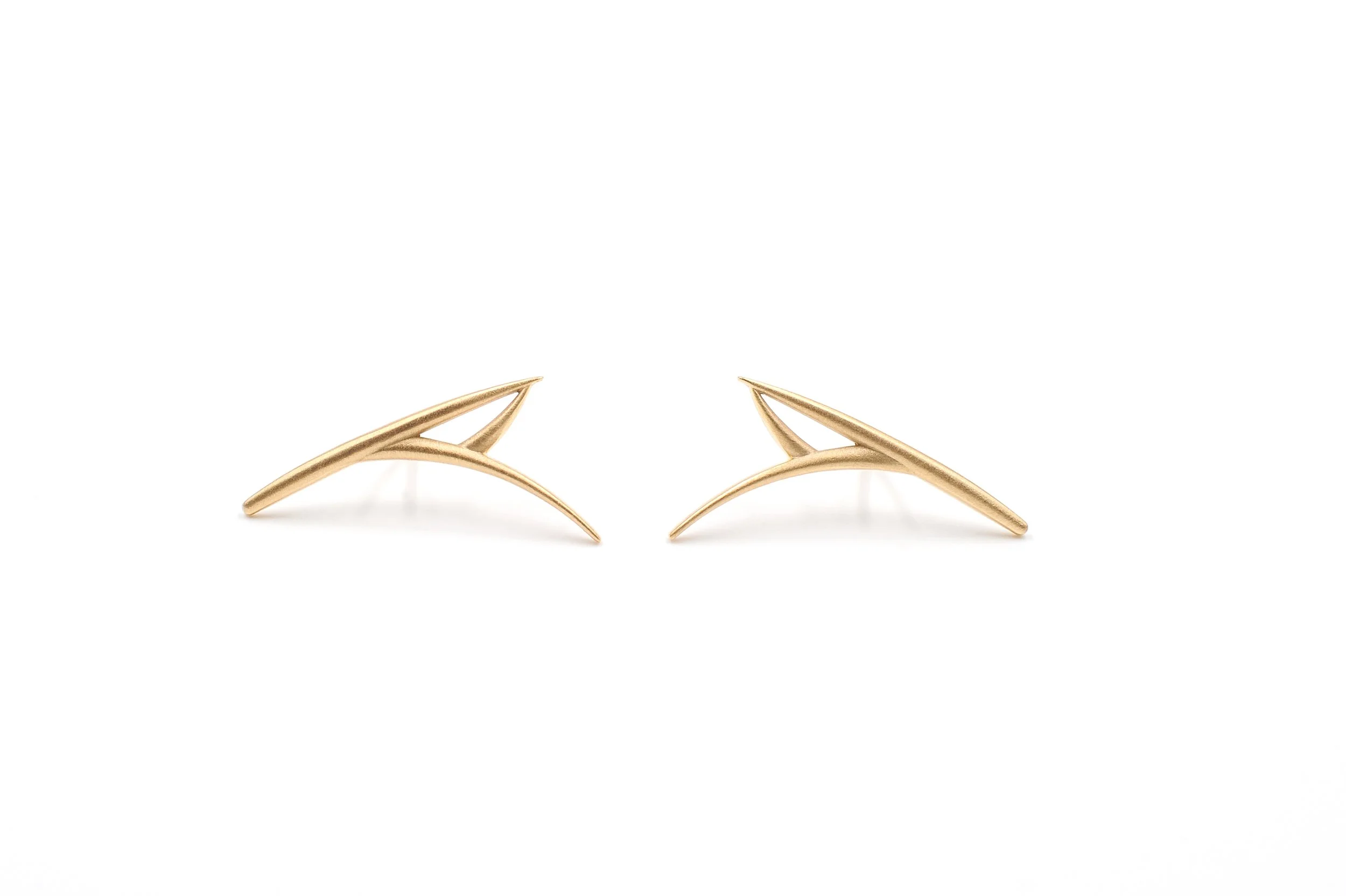 Gold-colored leaf-shaped earrings on a white background.