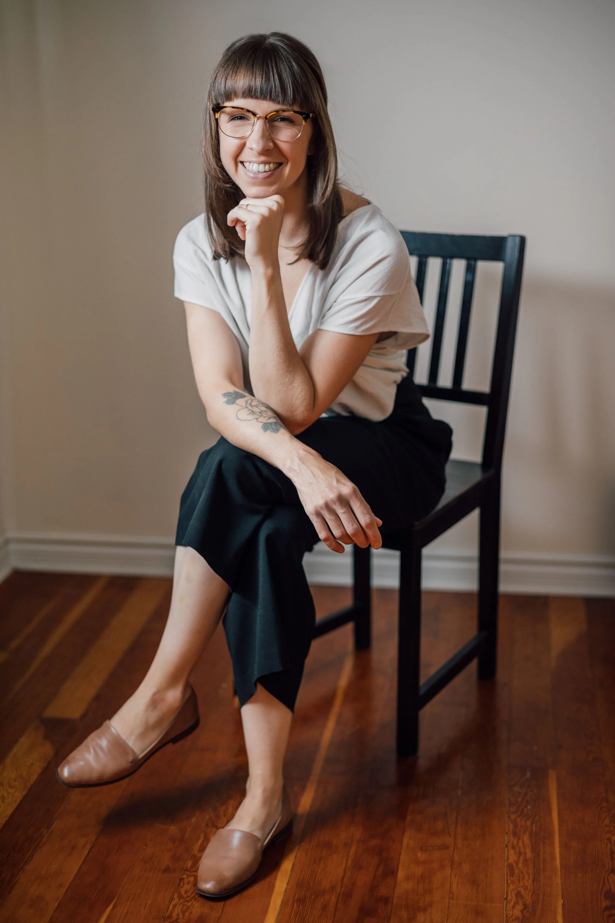 Angie, administrative support at grow onwords, seated on a chair and smiling toward the camera.