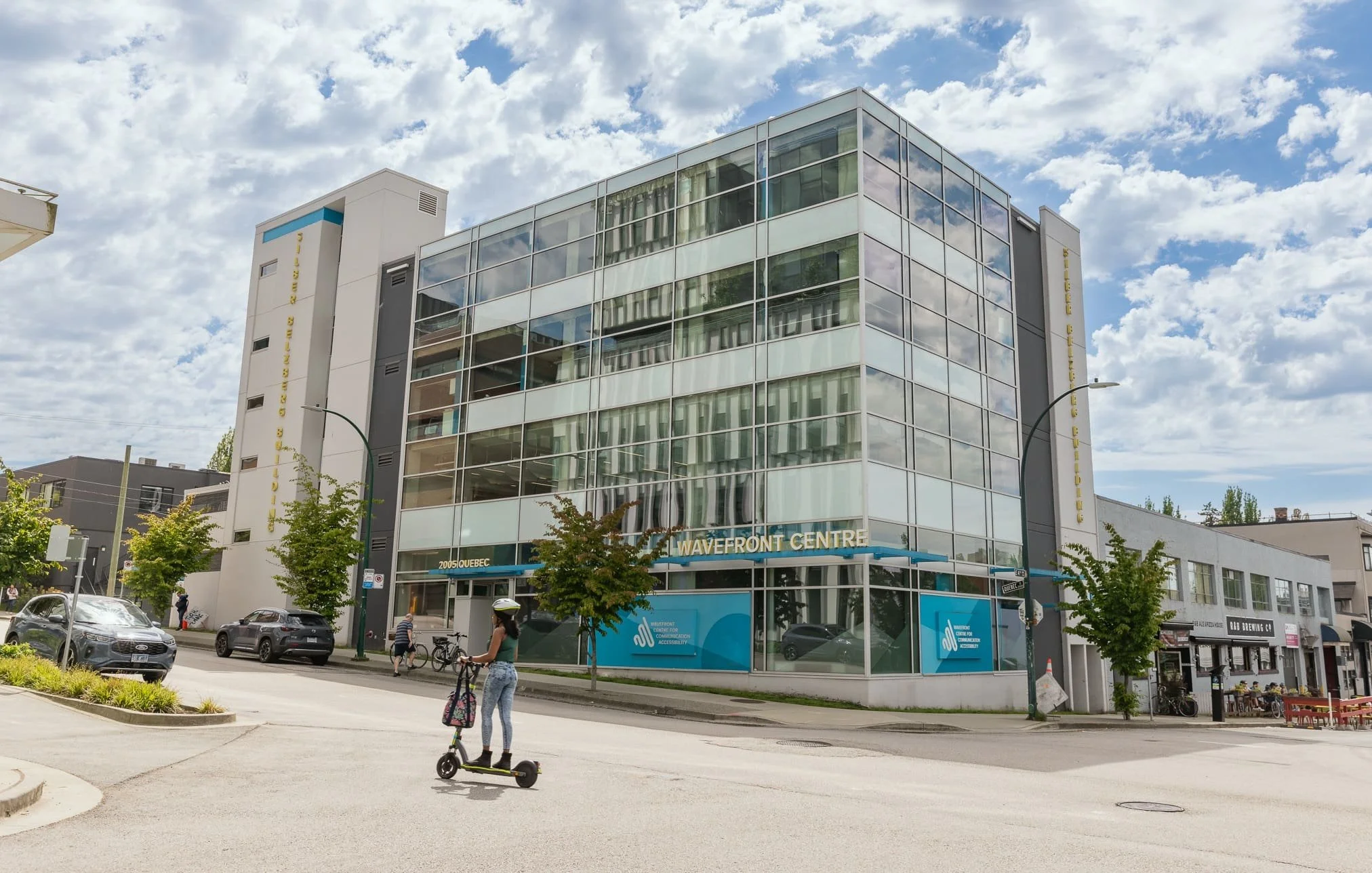 Exterior of the building at 2005 Quebec Street in Vancouver, home to The SPOT Pediatric Centre in Vancouver, a modern glass building with street-level signage for Wavefront Centre.