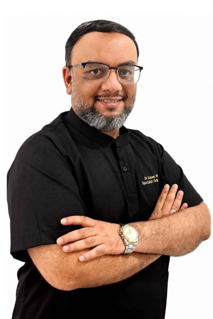 A man with glasses and a gray beard wearing a black medical uniform with his arms crossed, smiling against a white background.