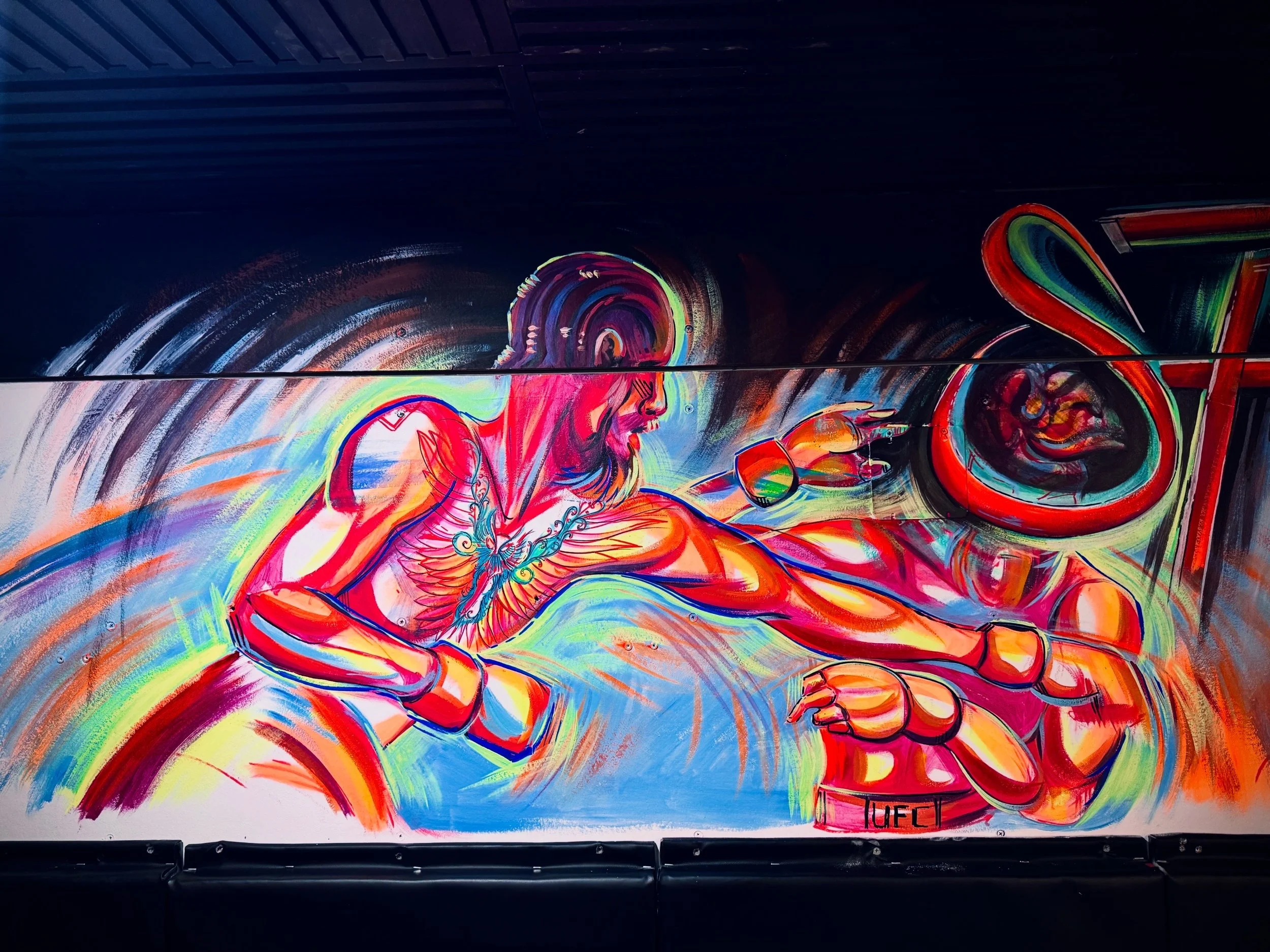 Colorful mural of a woman with a braid holding a phone, with a ring on her finger and a tattoo on her arm, in a vibrant, expressive art style.