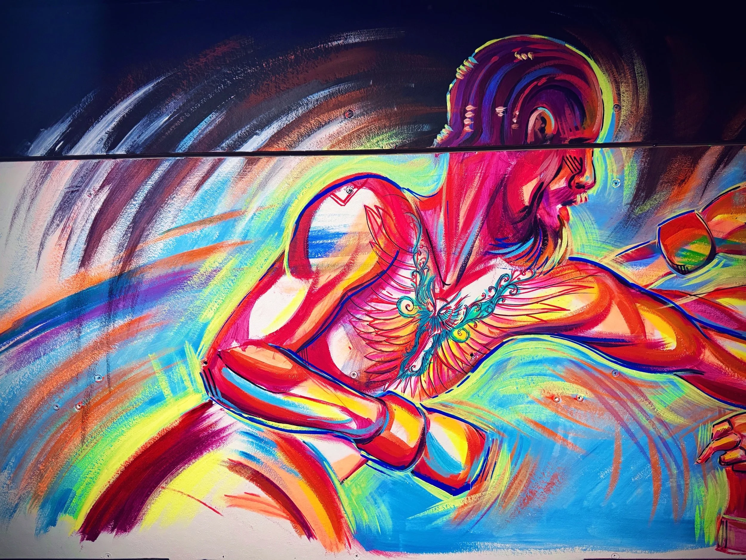 Colorful abstract mural featuring a person with long hair, possibly a woman, in a dynamic pose with bright, swirling colors including red, yellow, blue, and purple.