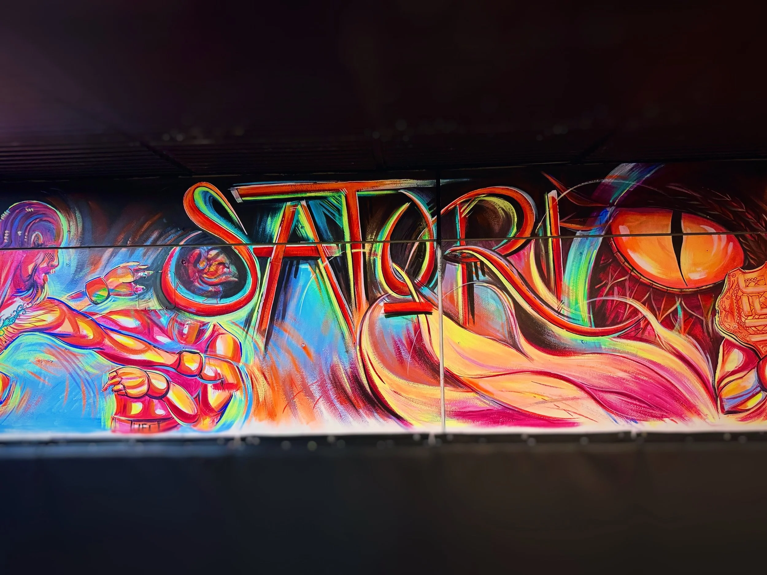 Bright neon graffiti art with the word 'TARS' in colorful, stylized letters, featuring abstract designs and a figure on the right side.