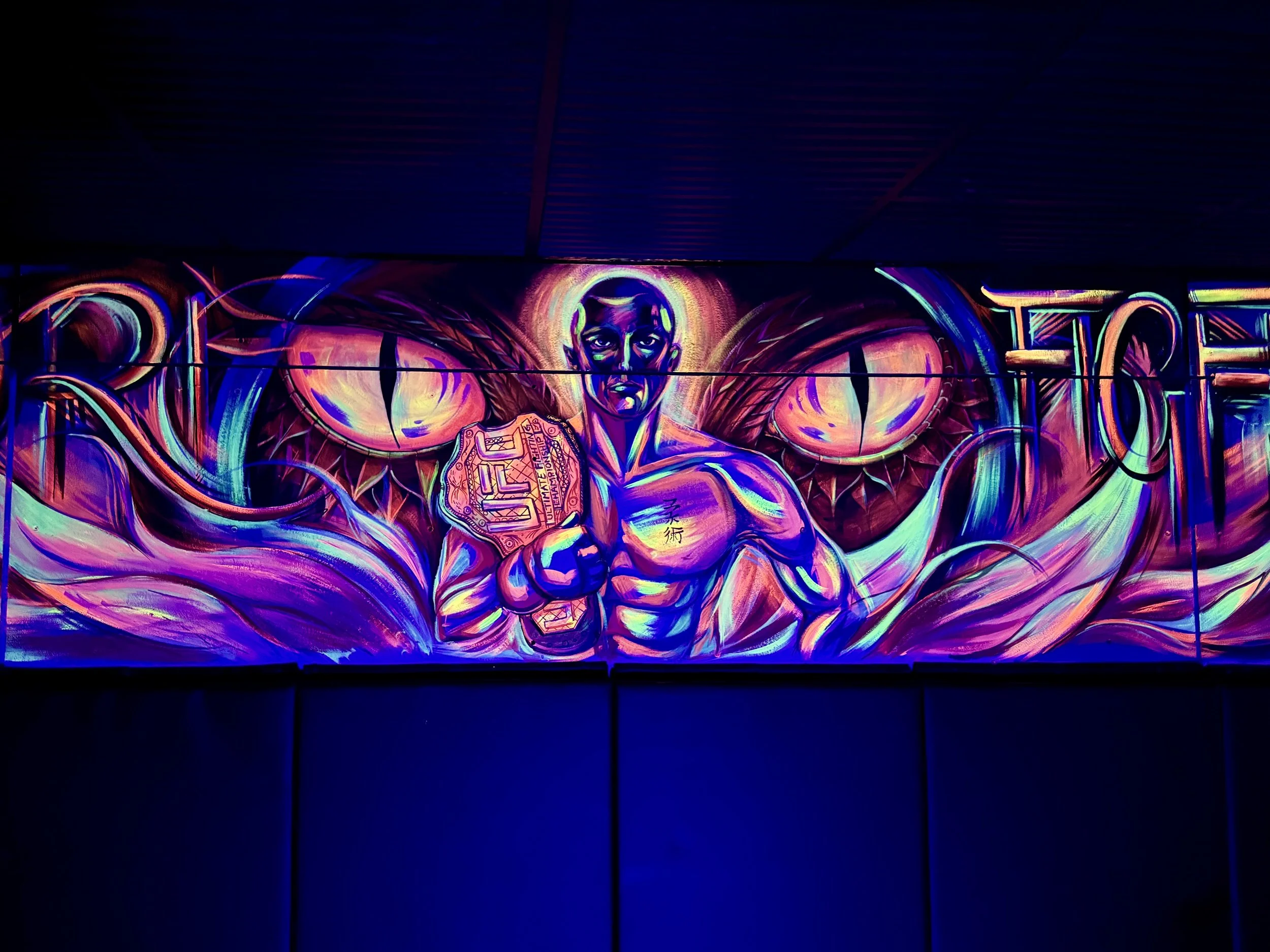 Neon-style mural of a boxer with neon colors and abstract background, illuminated against a dark wall.