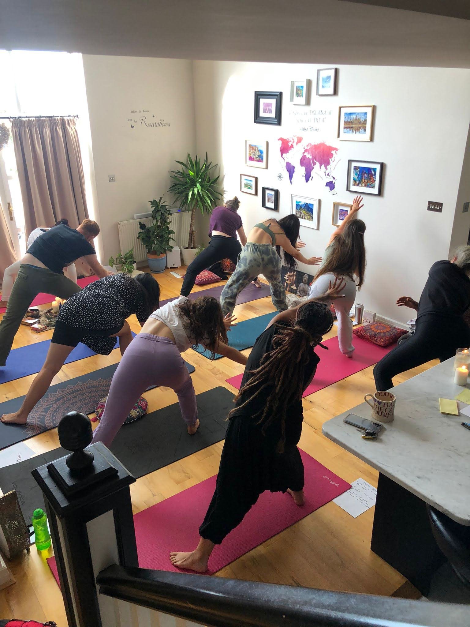 People participating in a yoga class in a living room with artwork and a world map on the wall.