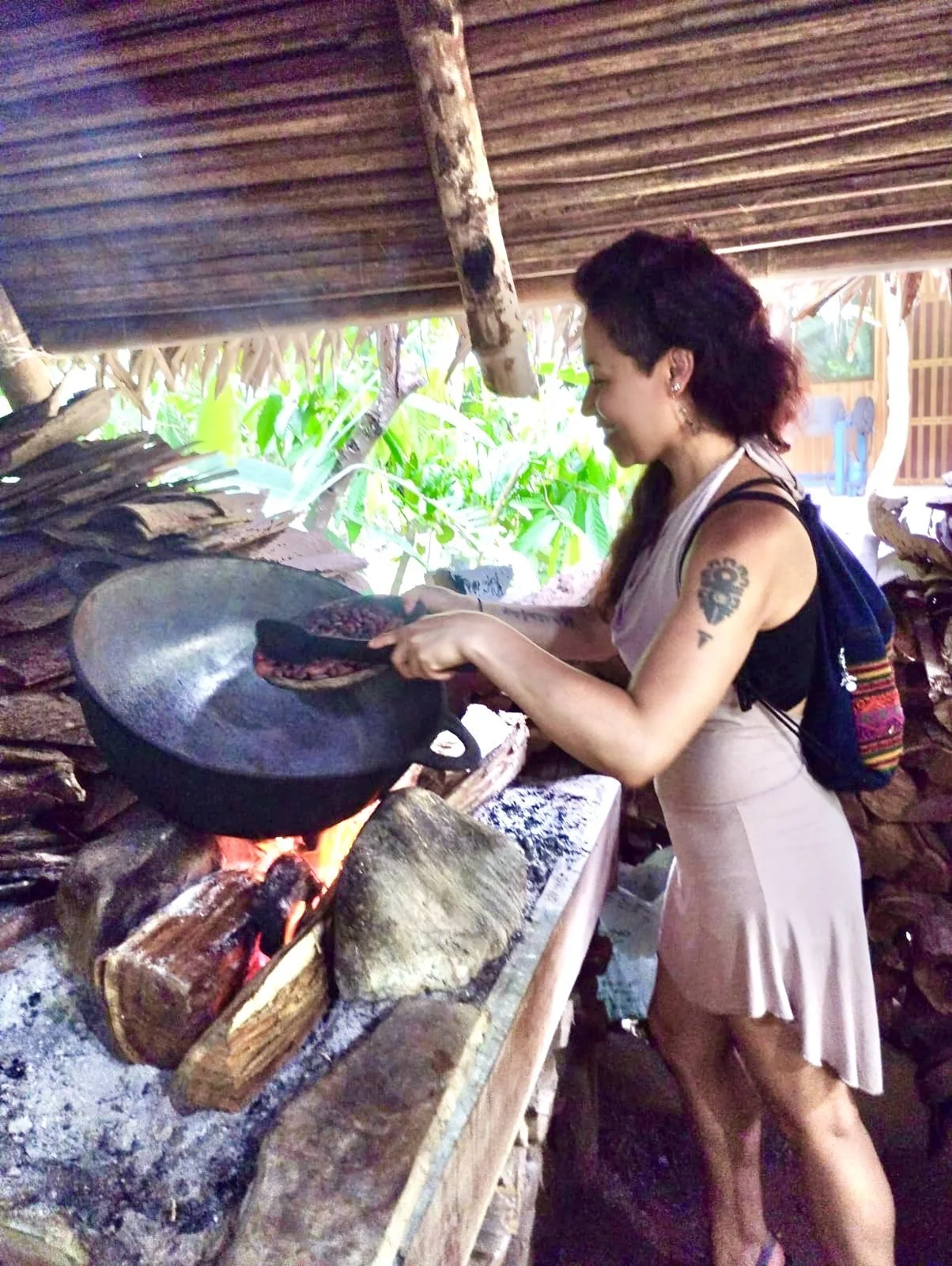 Woman cooking over an open fire on a rustic outdoor stove.