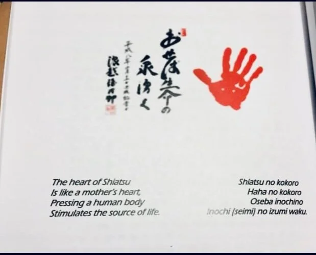 A page with Japanese calligraphy, a red handprint, and English translation about the heart of Shiatsu being like a mother's heart, pressing a human body to stimulate life.