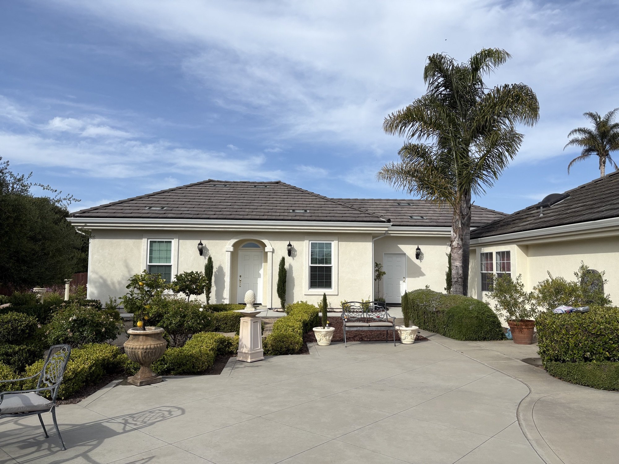 Residential exterior project with landscaped courtyard, stucco home, tile roof, and paved patio