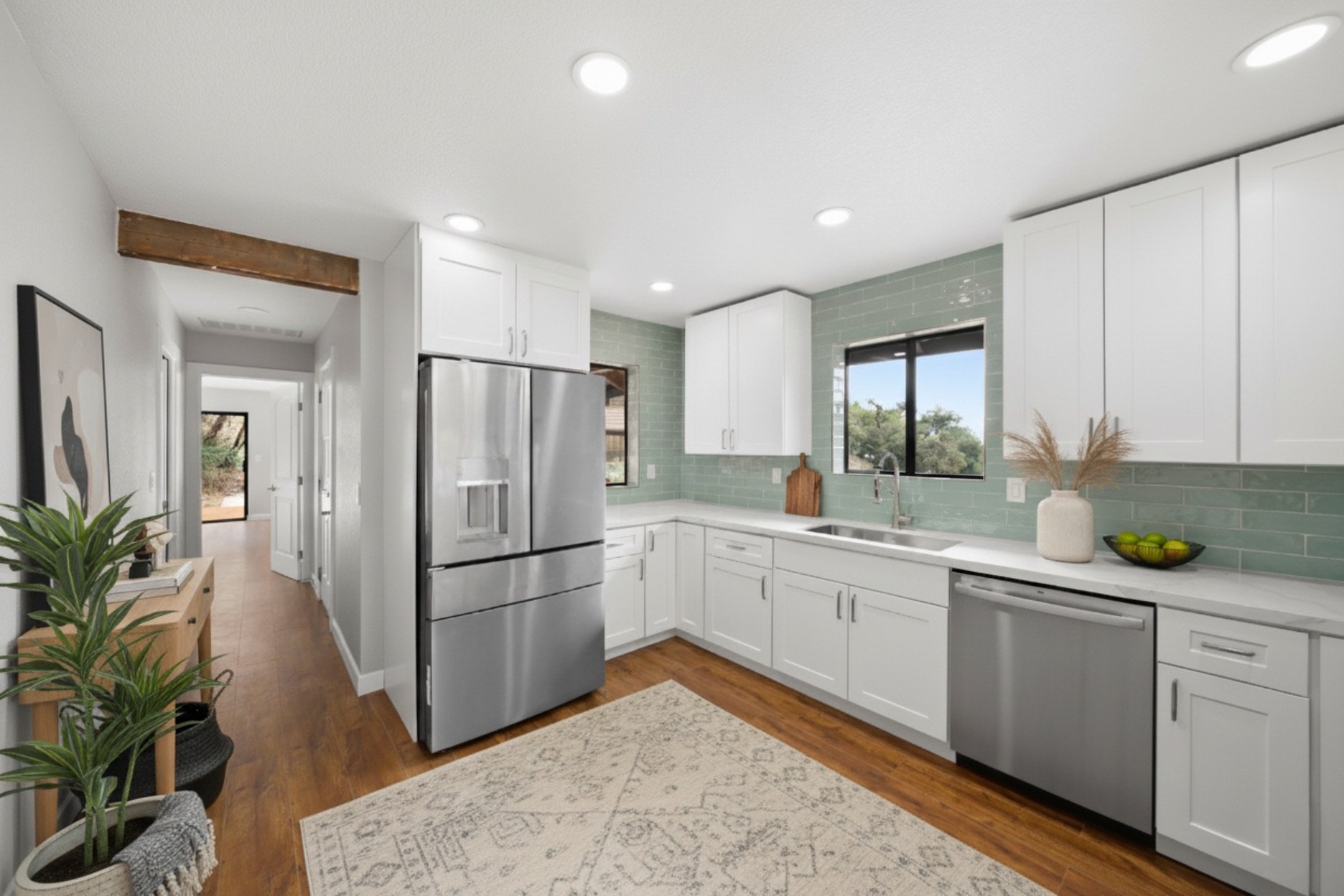 Completed kitchen remodel with white cabinets, green tile backsplash, stainless steel appliances, and wood flooring