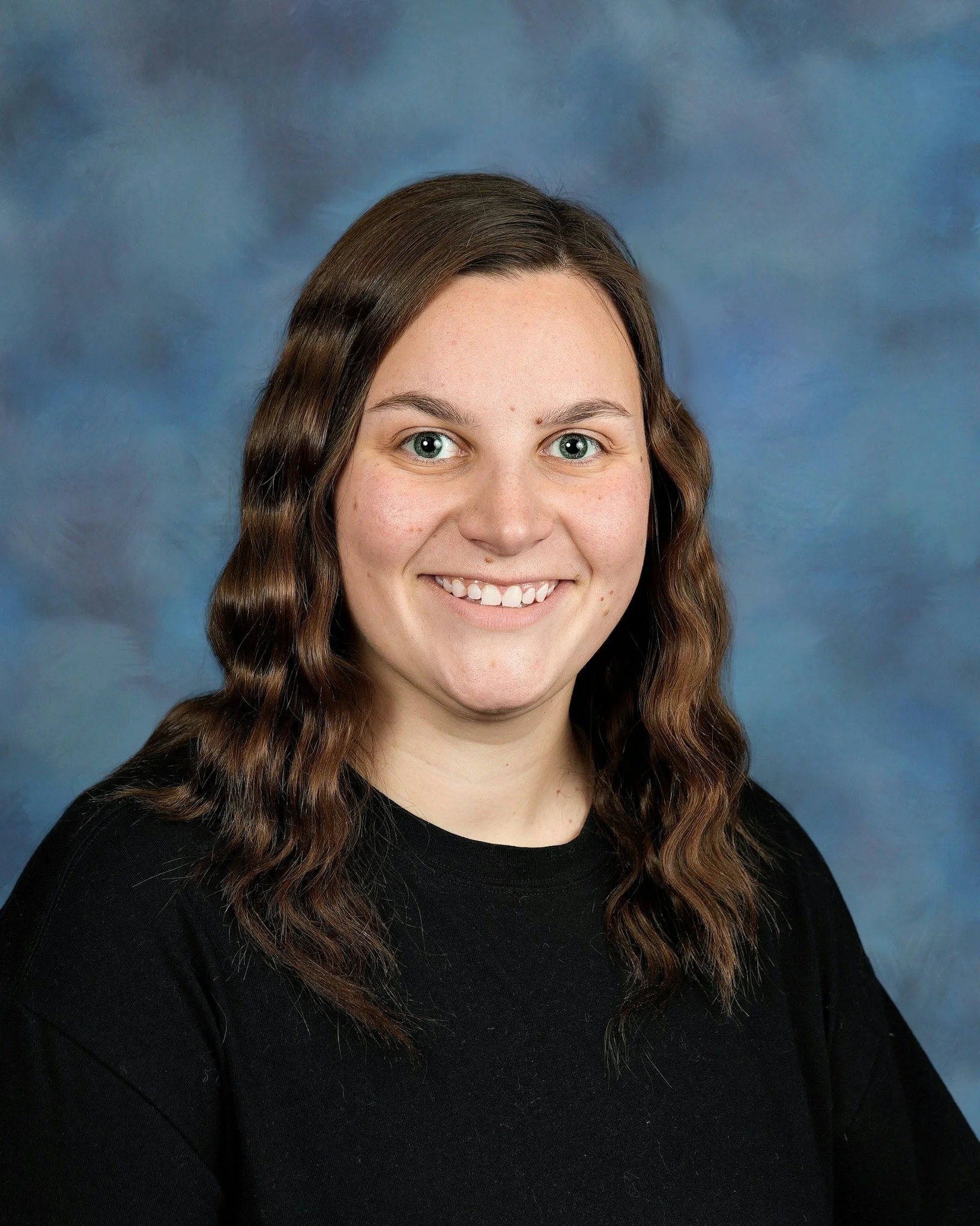 Young woman with wavy hair and a black shirt smiling