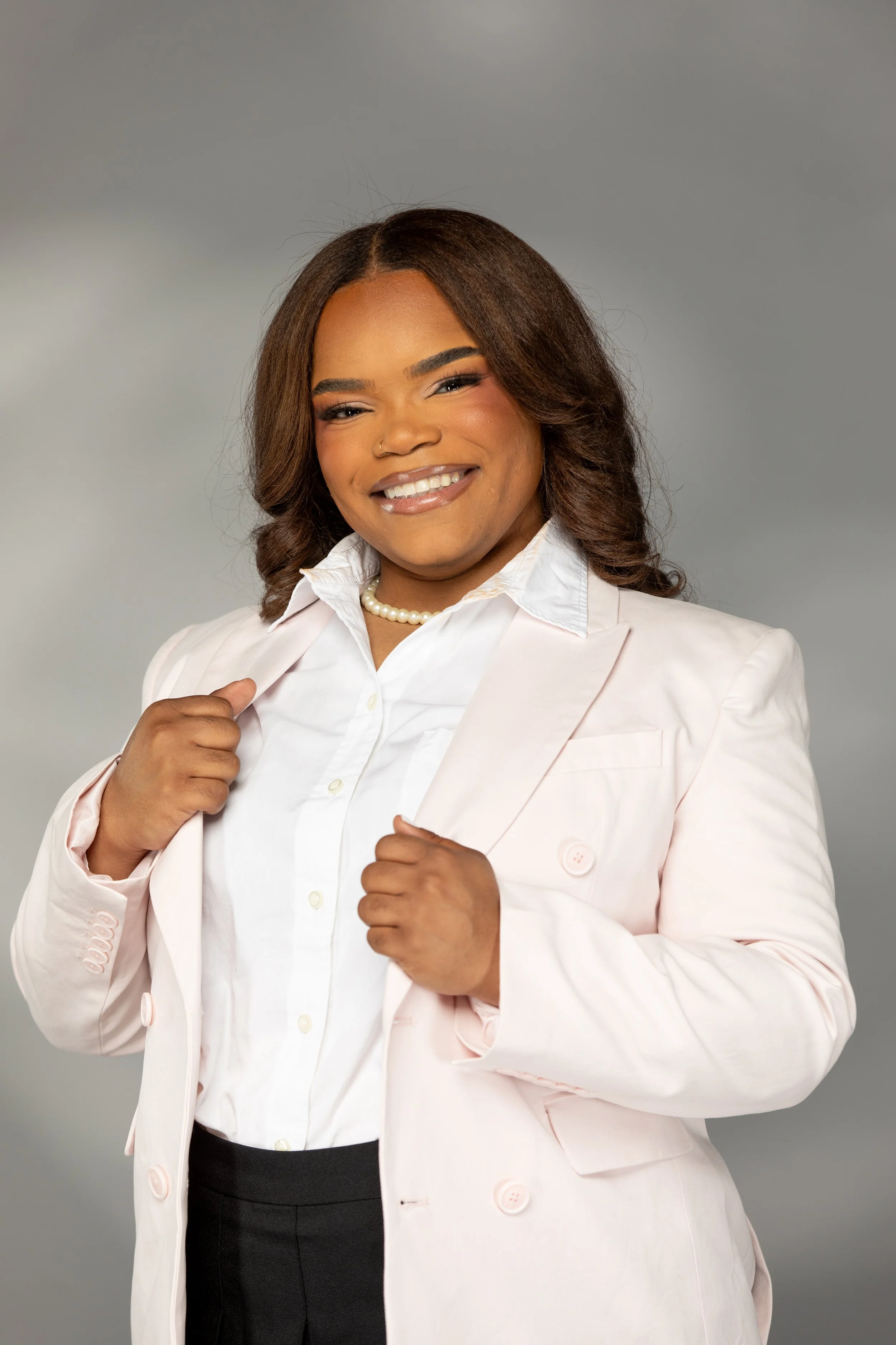 Smiling woman with curly hair holding lapels of suit coat