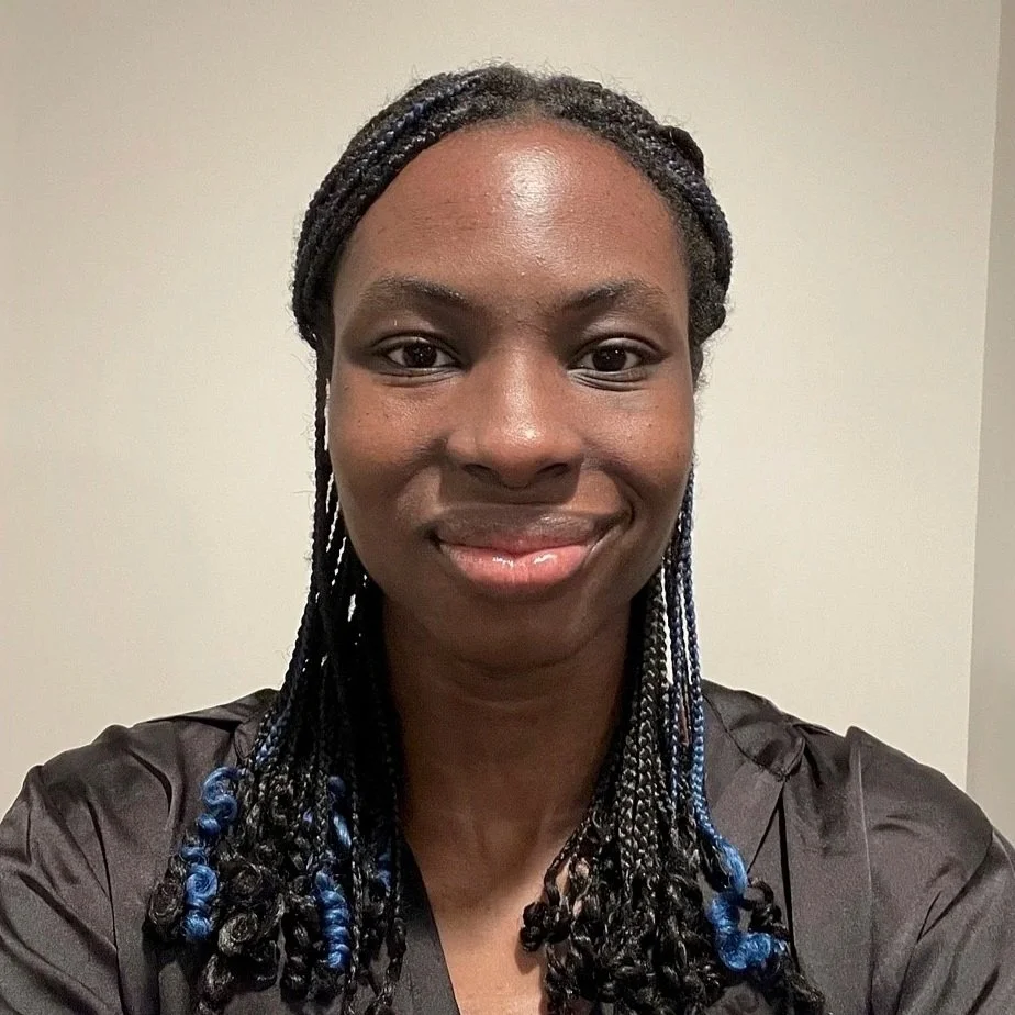 Smiling young woman with braided hair and a black blouse.