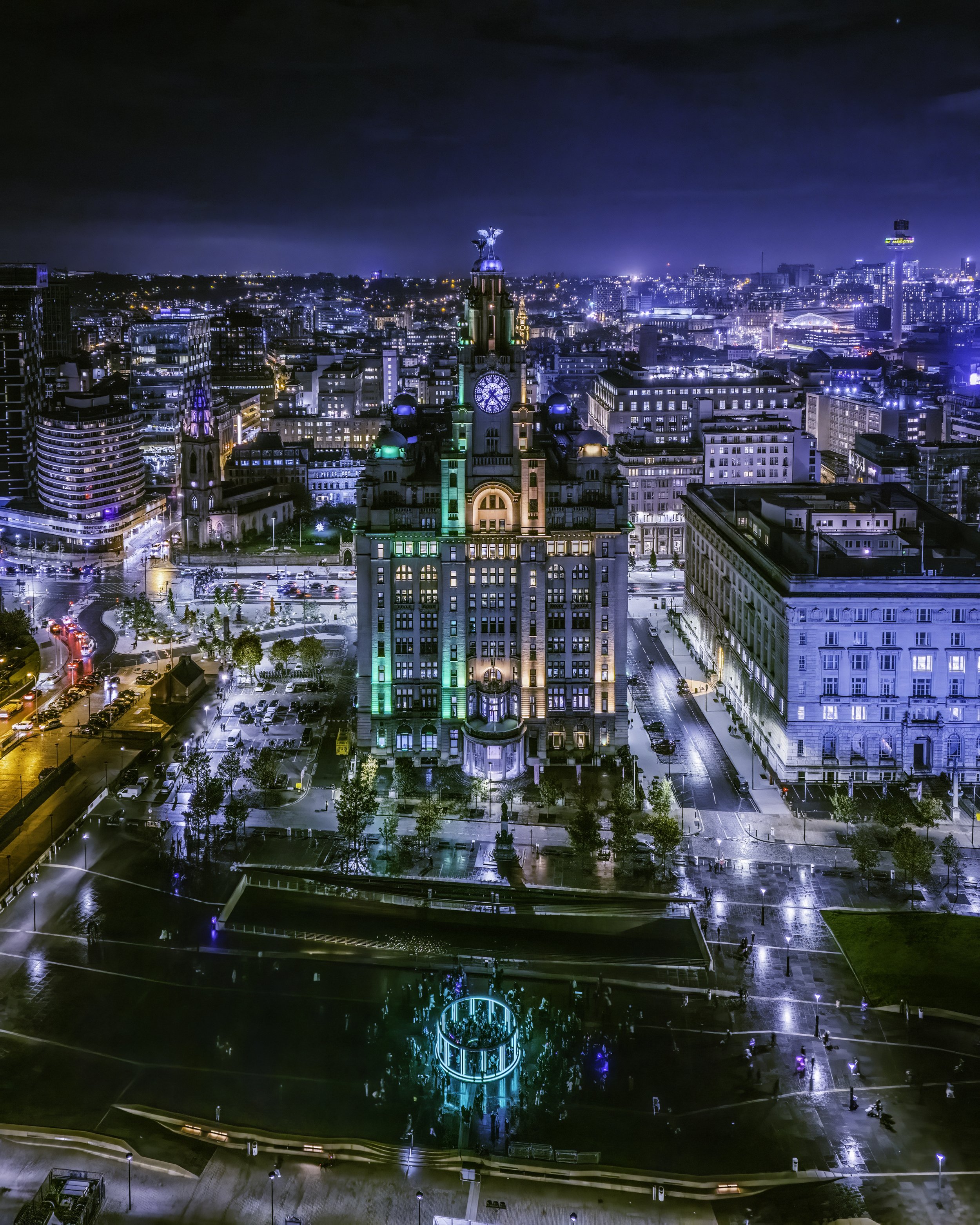 An aerial photograph of The Royal Liver Building lit up green and gold as part of the festival of lights event
