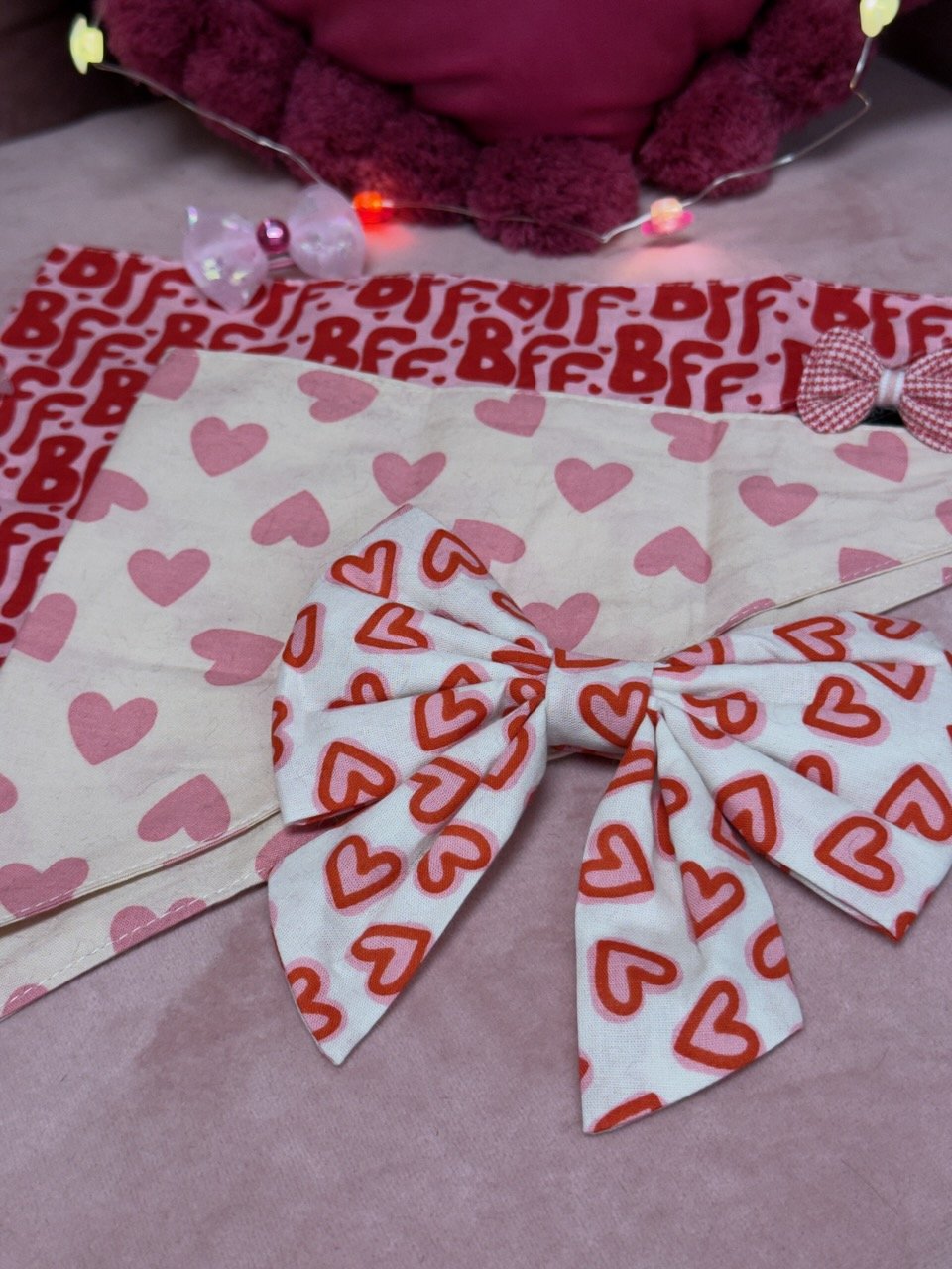 Valentine's Day-themed gift wrapped with heart-patterned fabrics, a bow, and decorative lights.