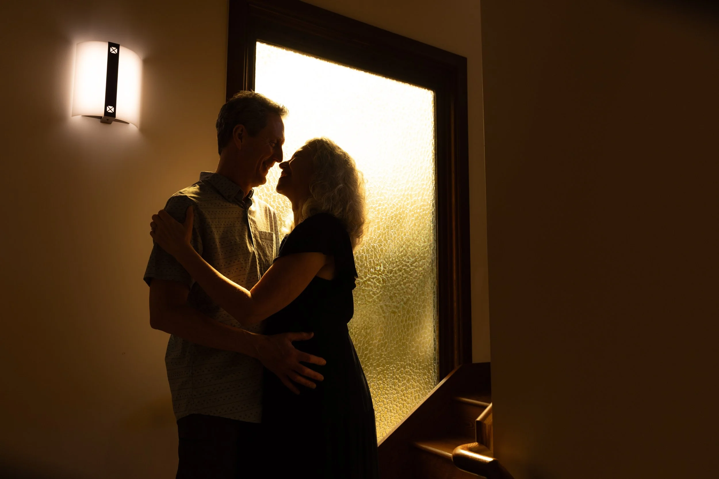 man and woman holding each other while smiling at each other in a stairwell  