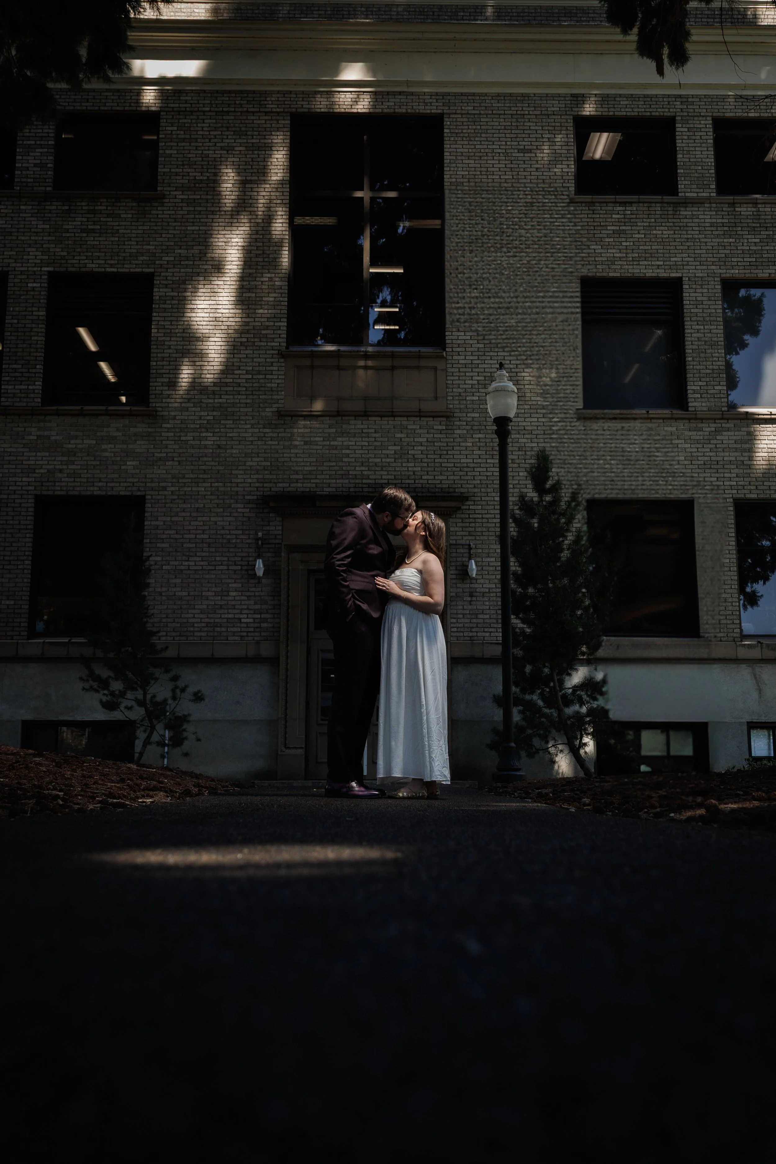 bride and groom illuminated in front of a court house during their elopement sharing a kiss