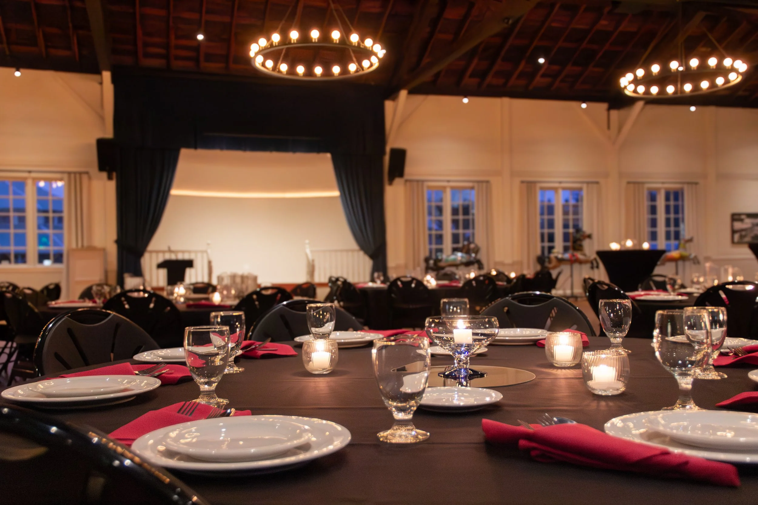a wedding place set with red napkins on a black table in a historic dance pavilion in sellwood oregon