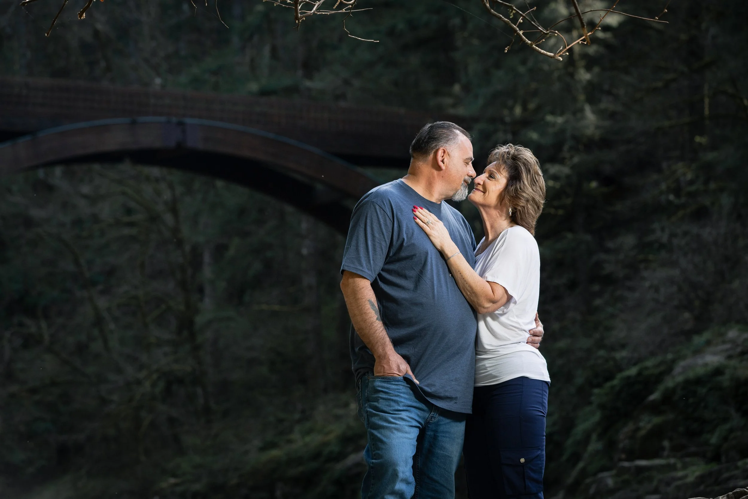 man and woman holding each other in front of moulton falls during an engagement photo shoot