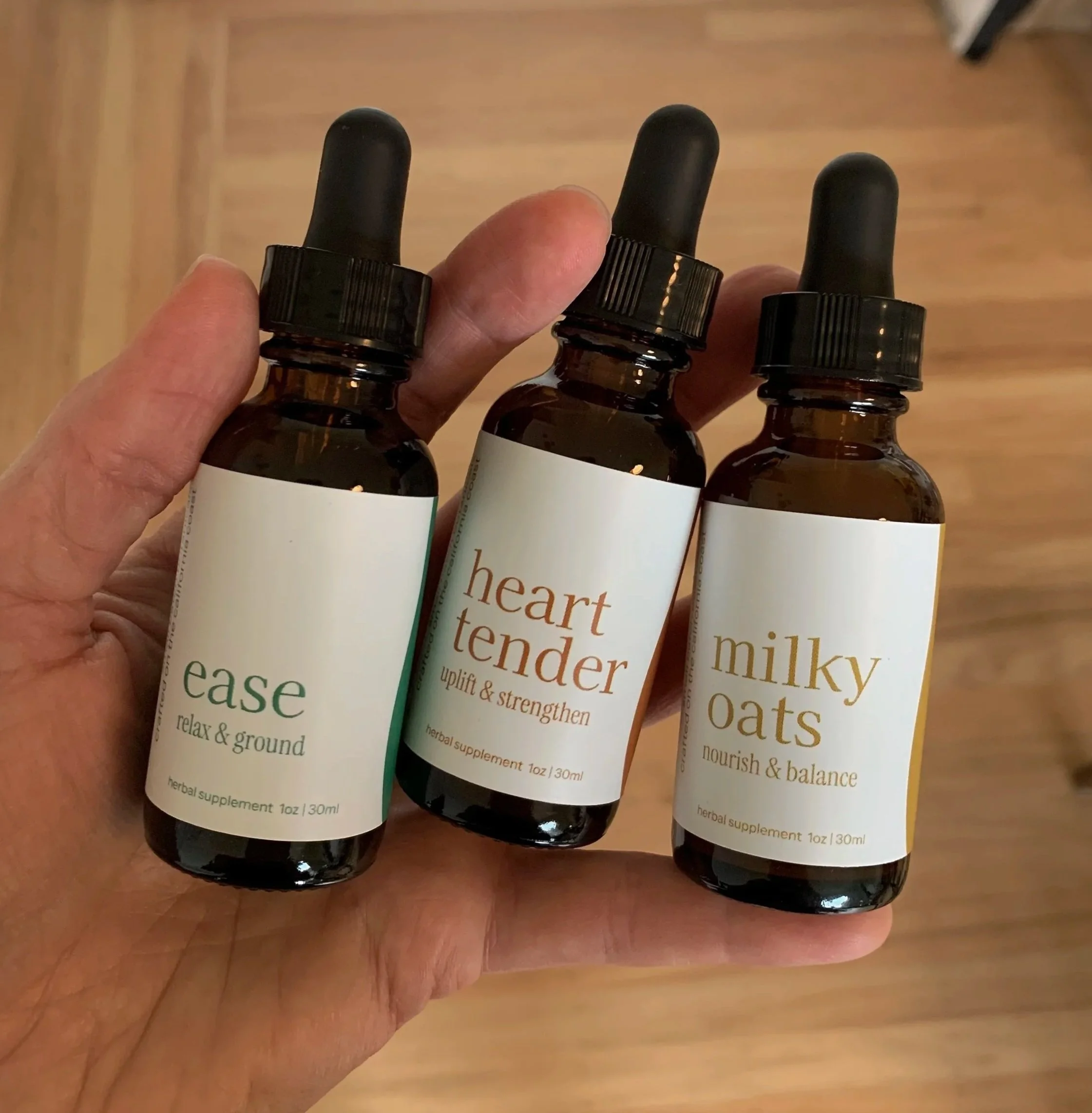 a hand holding three tincture bottles