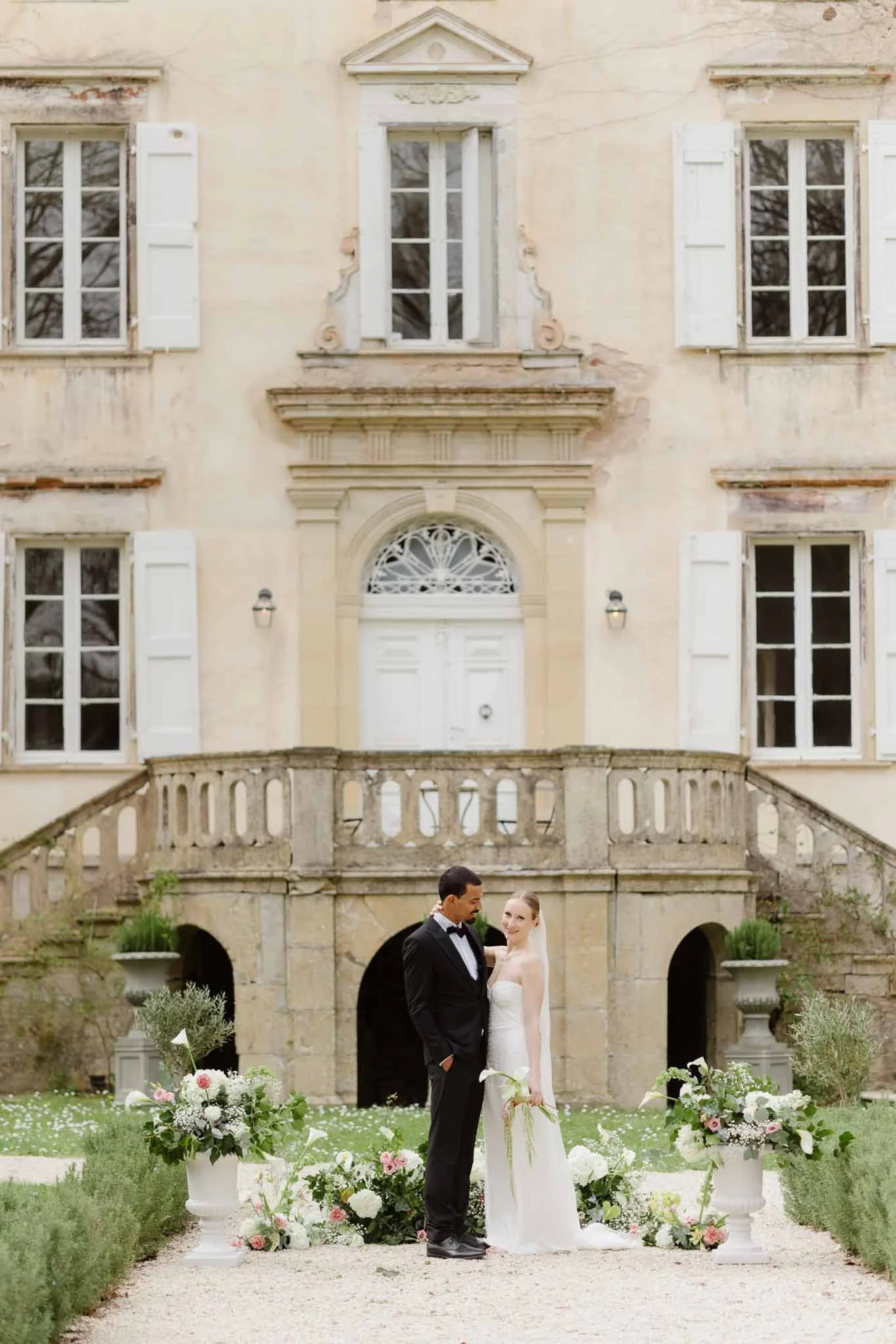 Chateau-du-Pont-Bourget-Lina-Bernard-bride-groom-hugging-standing-ceremony-altar-front-vintage-building.jpg