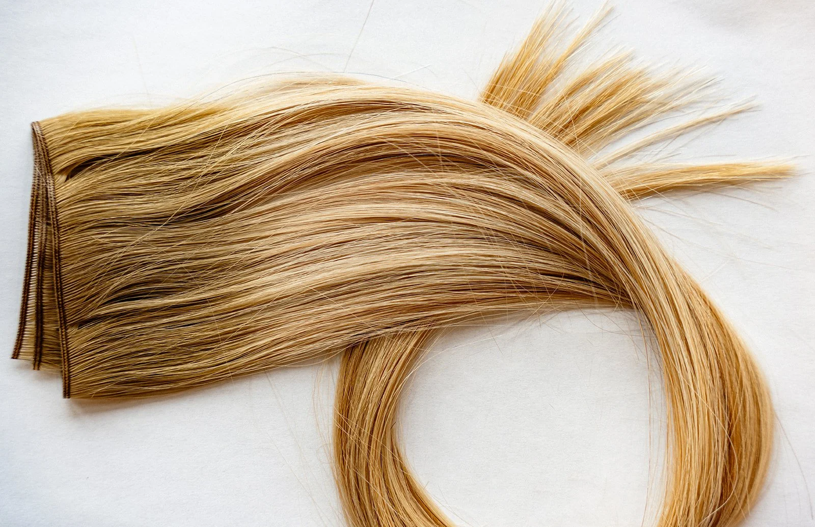 Close up of blonde hair extension on marble background.