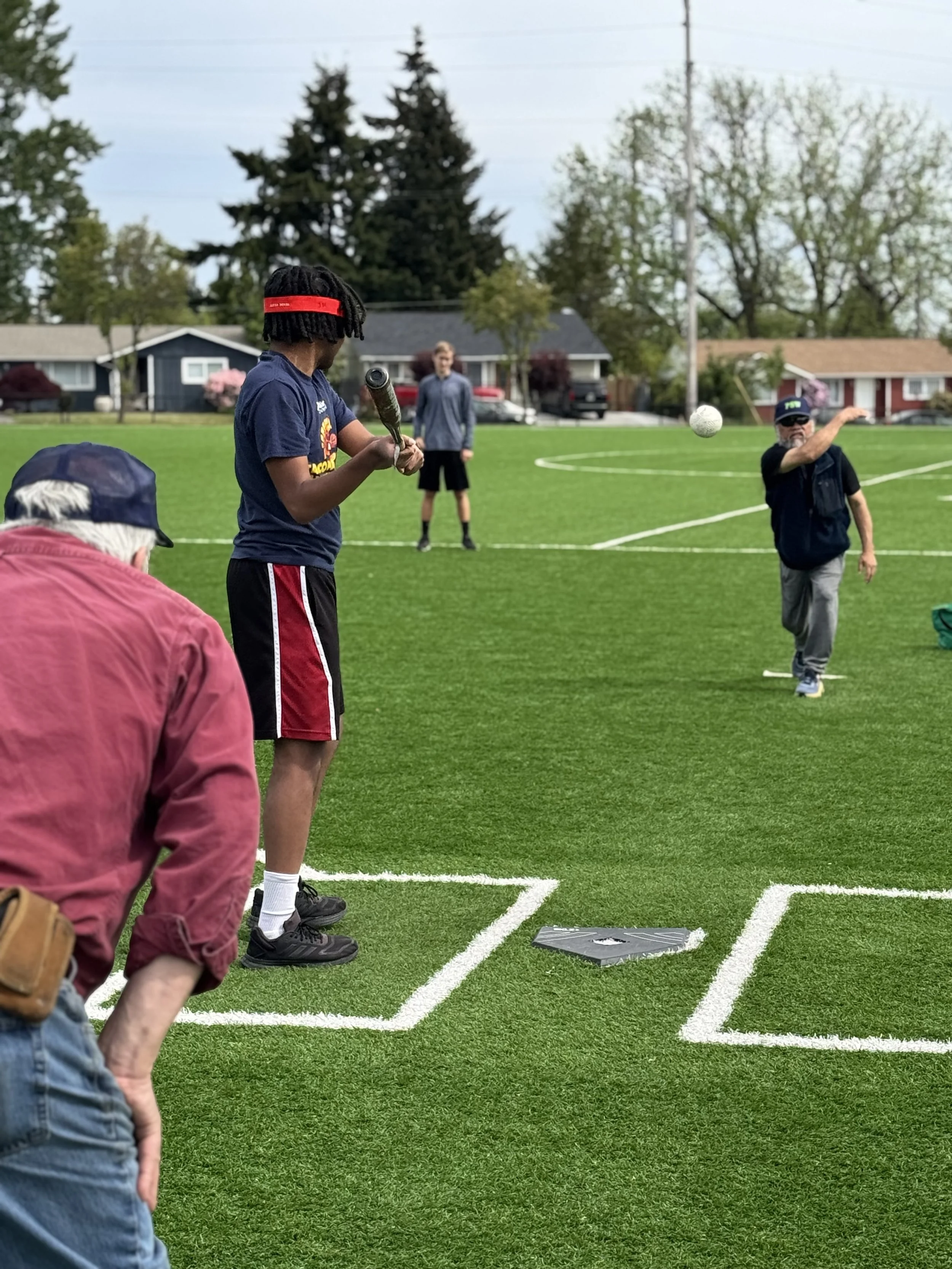 Beep baseball hitter up to bat on a sunny day wearing an eye covering