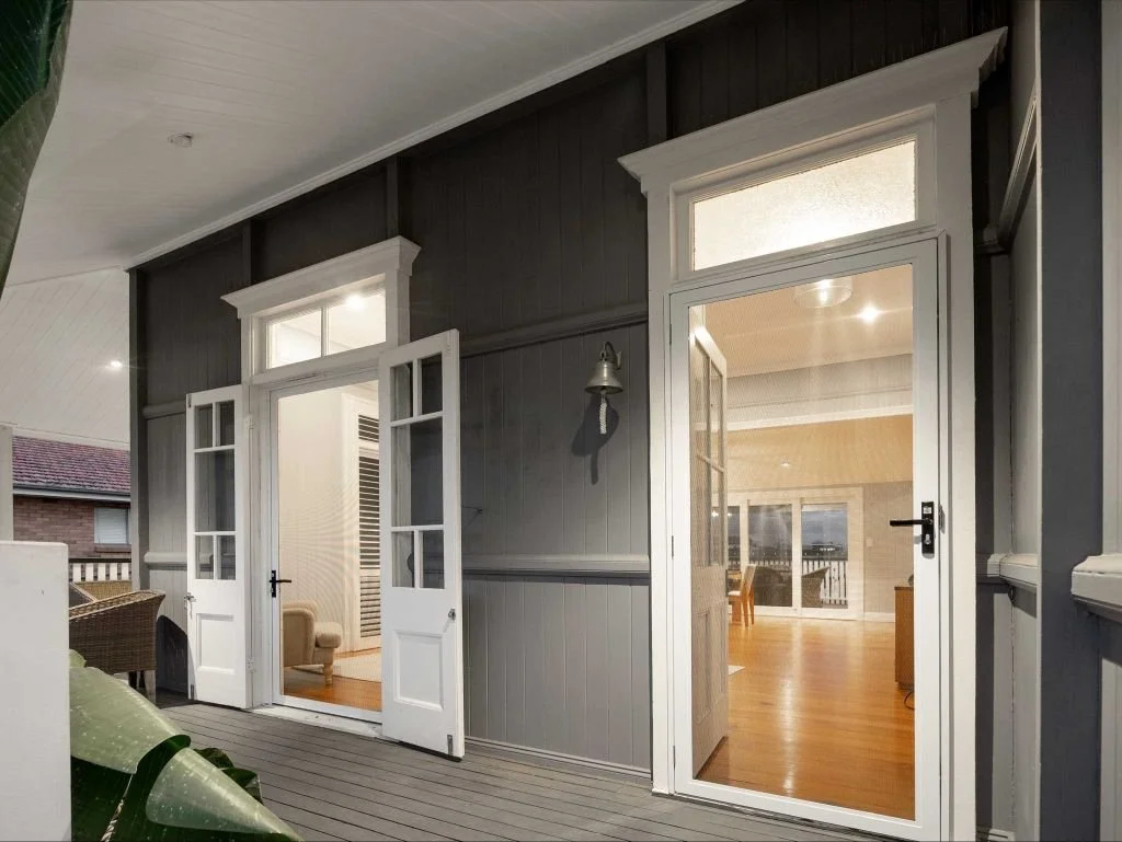 Exterior view of a house with open French doors and entry door both with stainless steel security screens installed