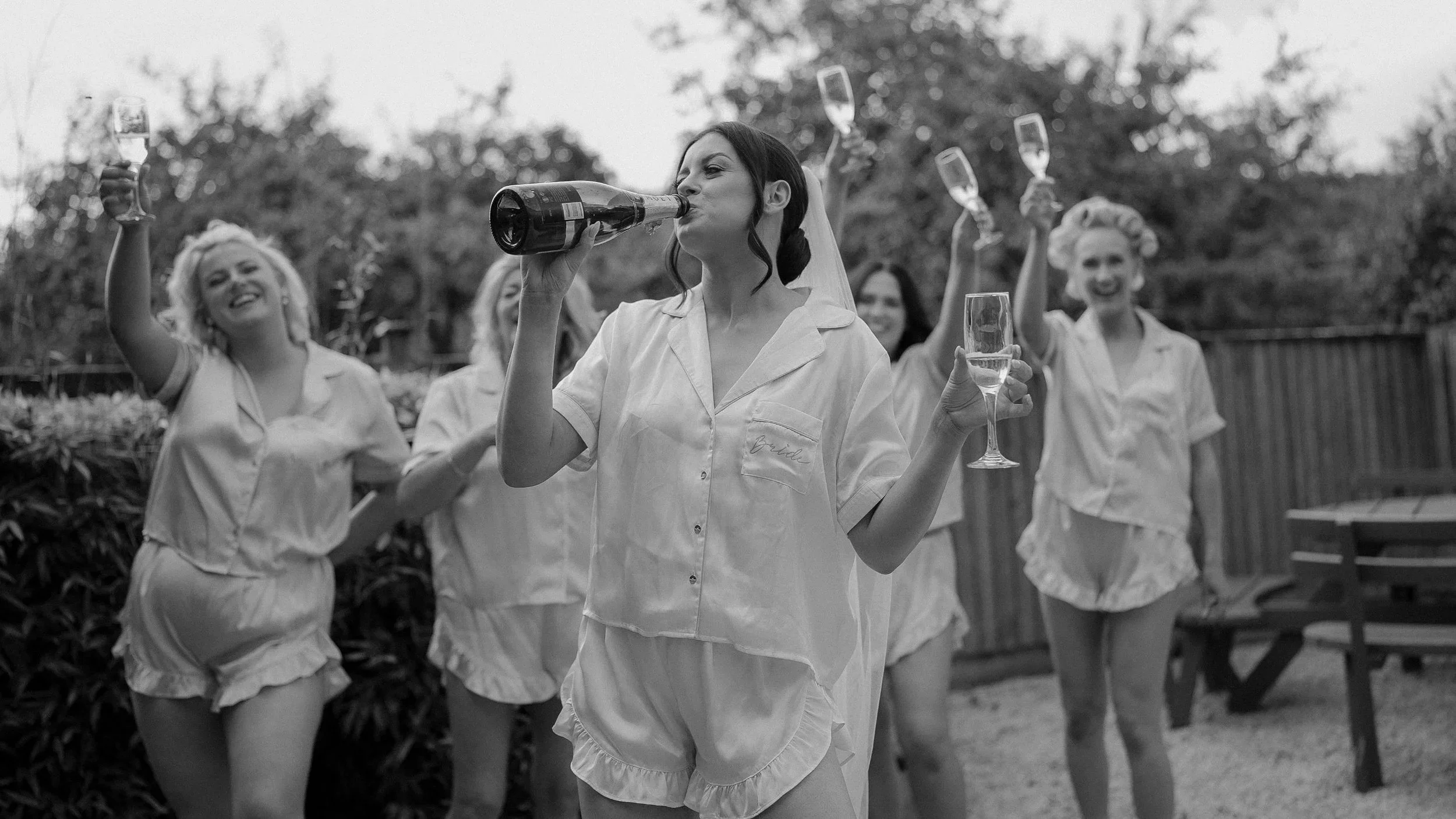 Bride and bridesmaids in pyjamas toasting with champagne on the morning of her Farnham Estate wedding