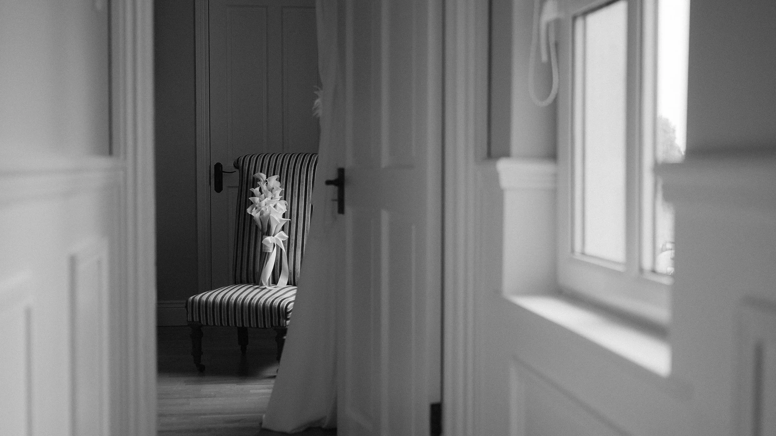 White calla lily bridal bouquet with ribbon on a striped chair, wedding morning, black and white