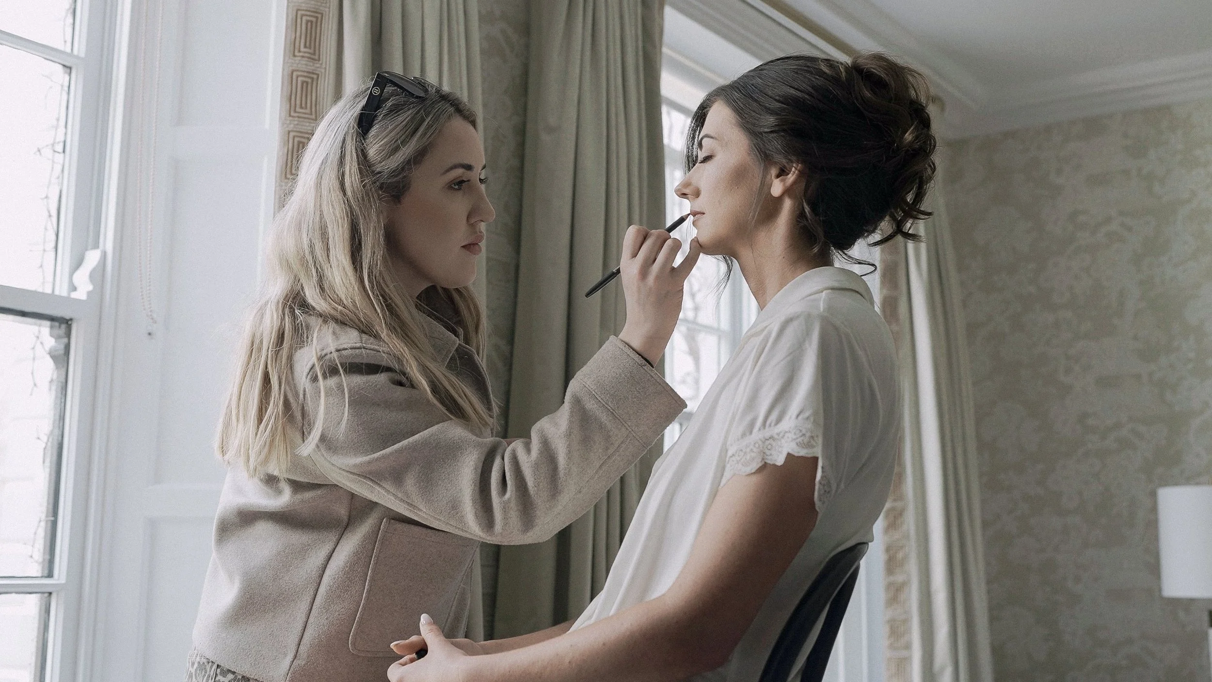 Make-up artist applying the bride's lip liner by the window on the wedding morning at Barberstown Castle