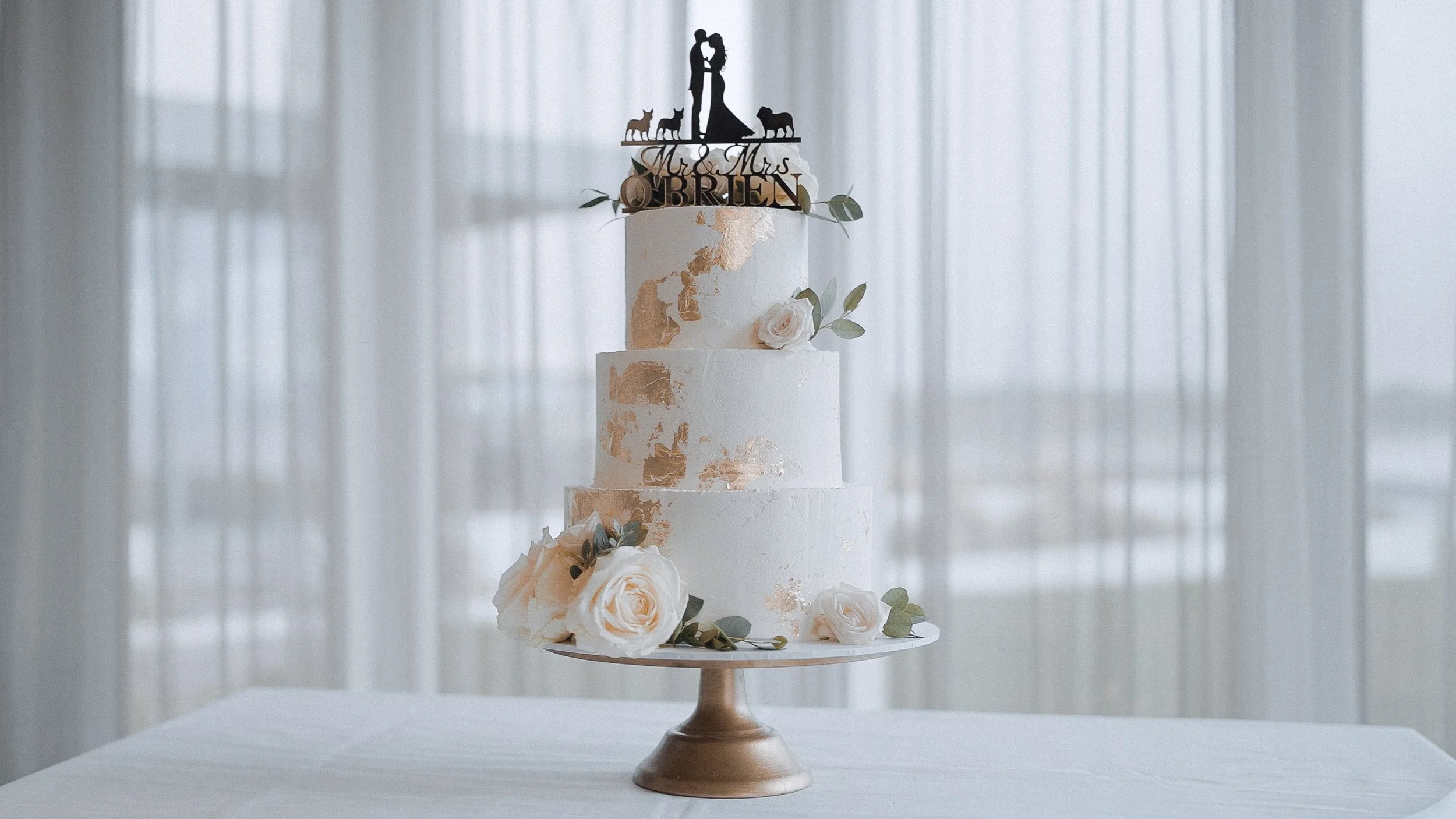 Three-tier white wedding cake with gold leaf, blush roses and a personalised topper at the Armada Hotel, Spanish Point