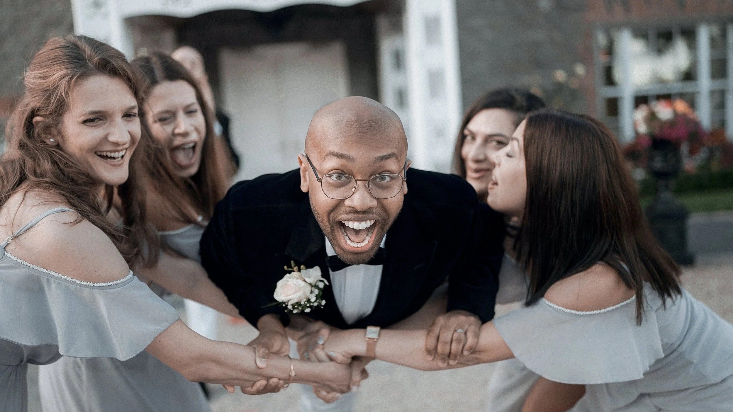 Bridesmaids in grey playfully pulling the groom in front of Darver Castle