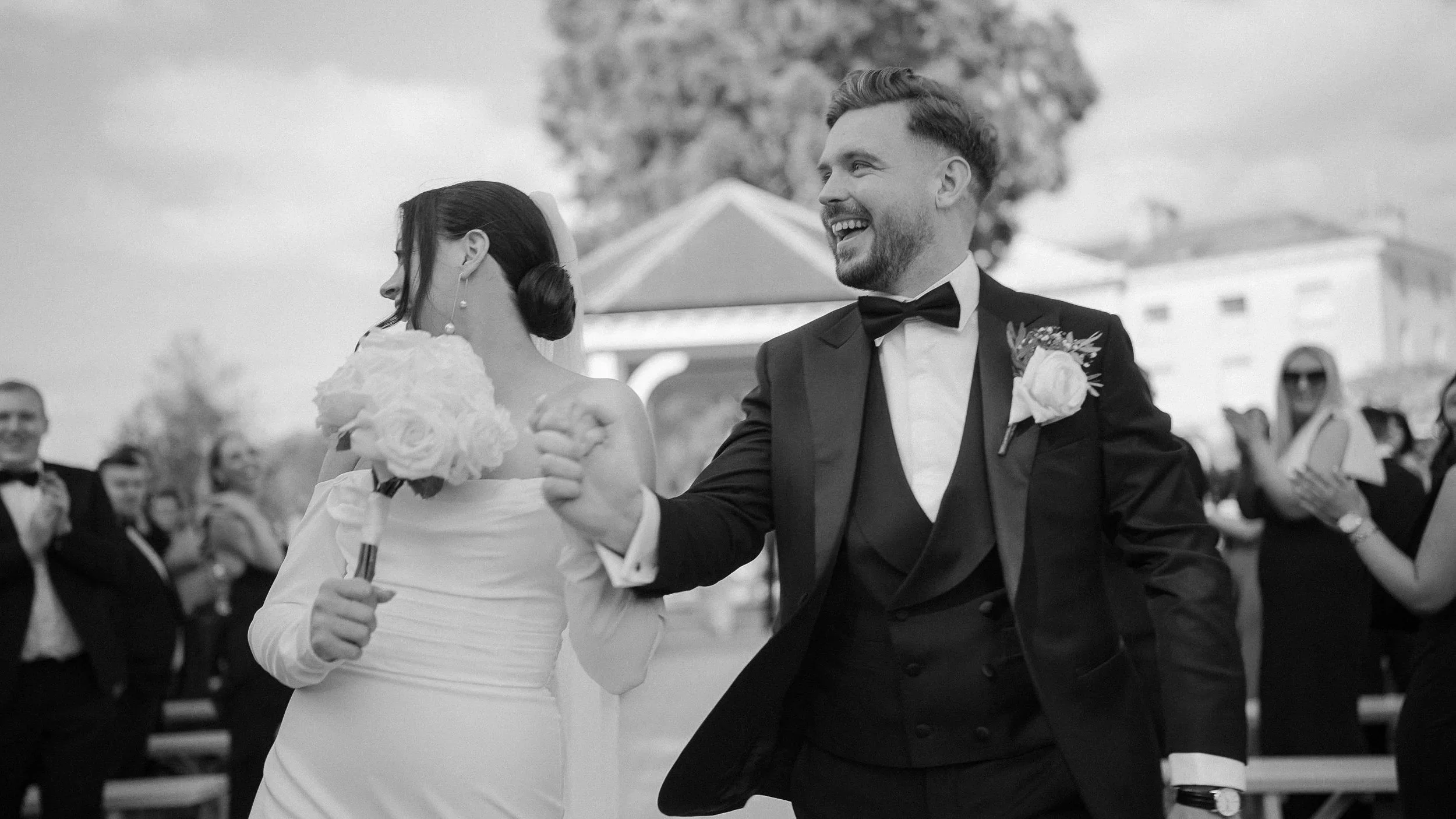 Black and white photo of Jennie and Craig walking hand in hand at Farnham Estate