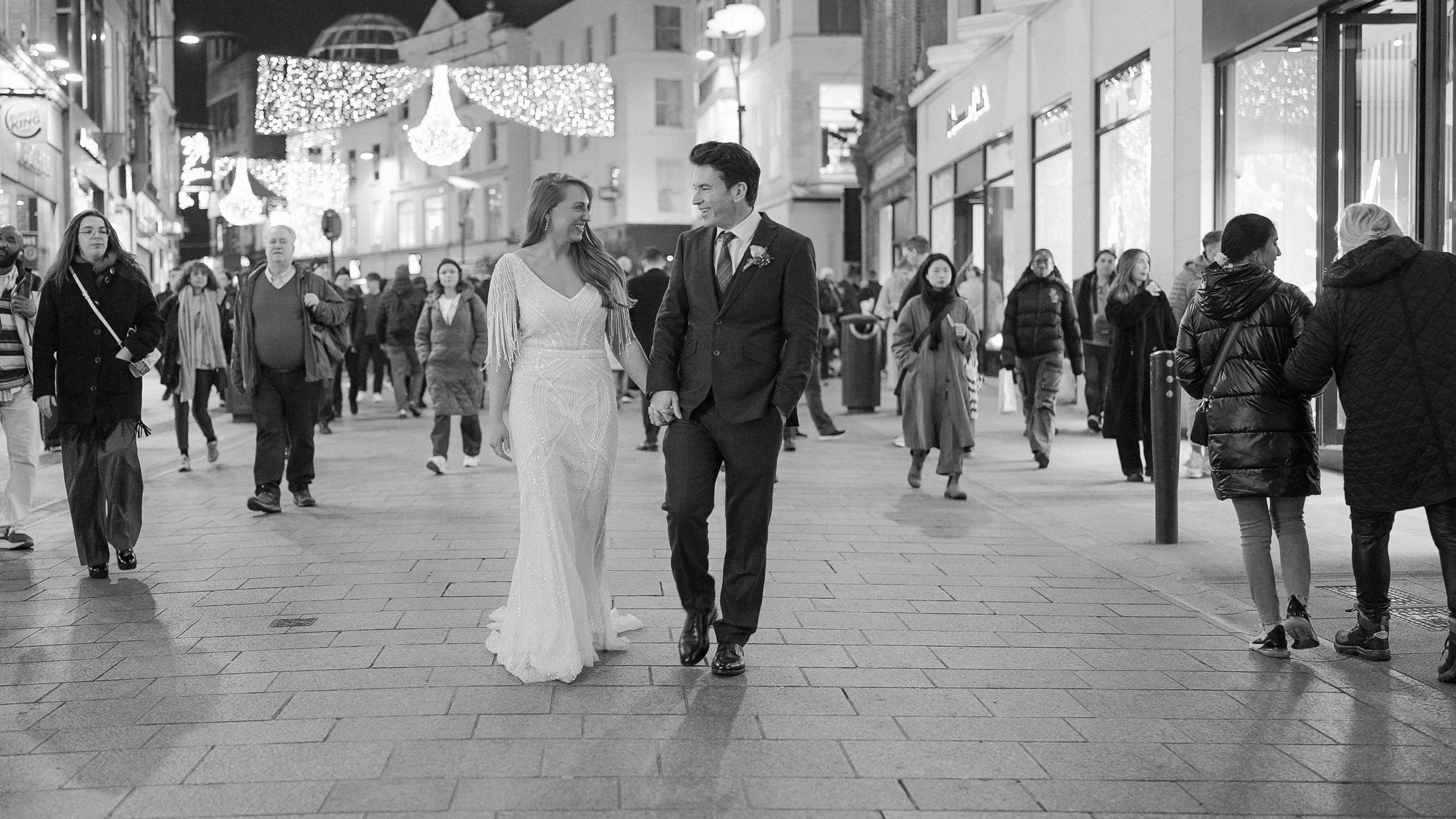 Newlyweds walking through Dublin city centre under the Christmas lights at night
