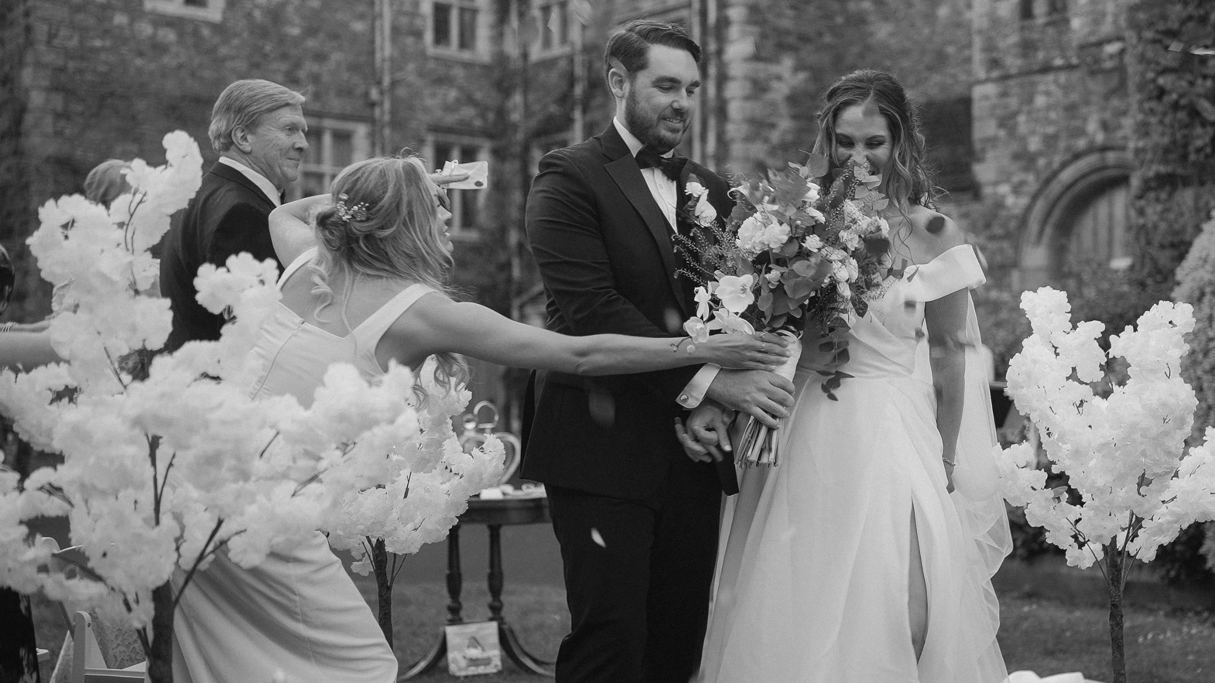 Guests showering the bride and groom with confetti outside Waterford Castle, black and white