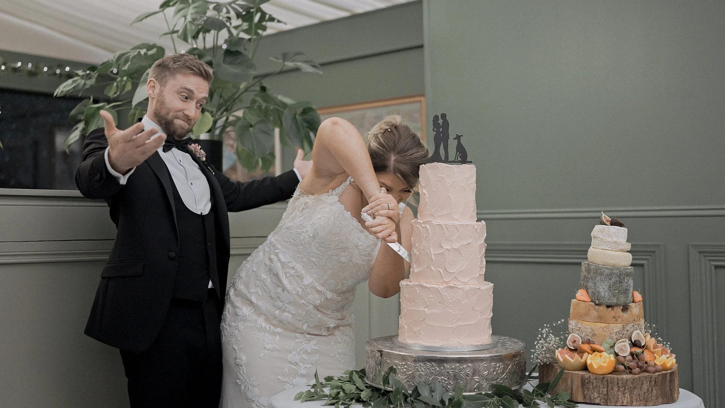Bride and groom cutting their peach buttercream wedding cake next to a cheese tower at Tinakilly Country House