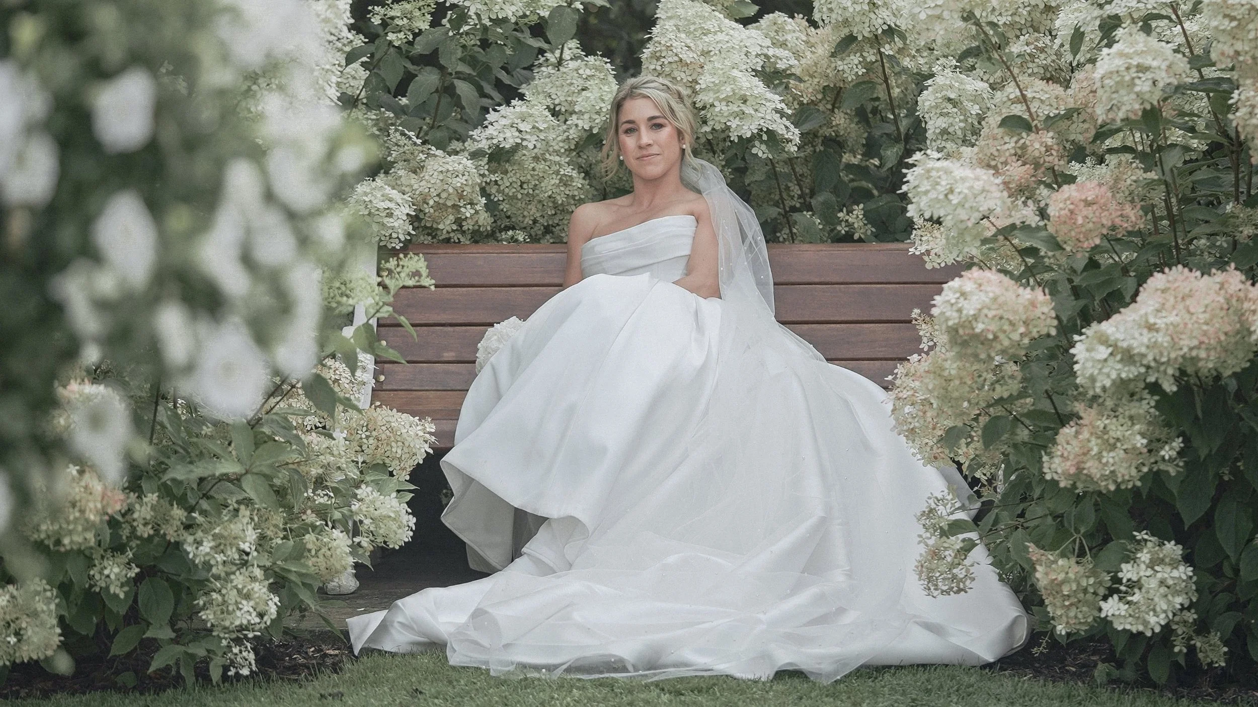 Bride on a garden bench among white hydrangeas at a family home wedding in Kildare