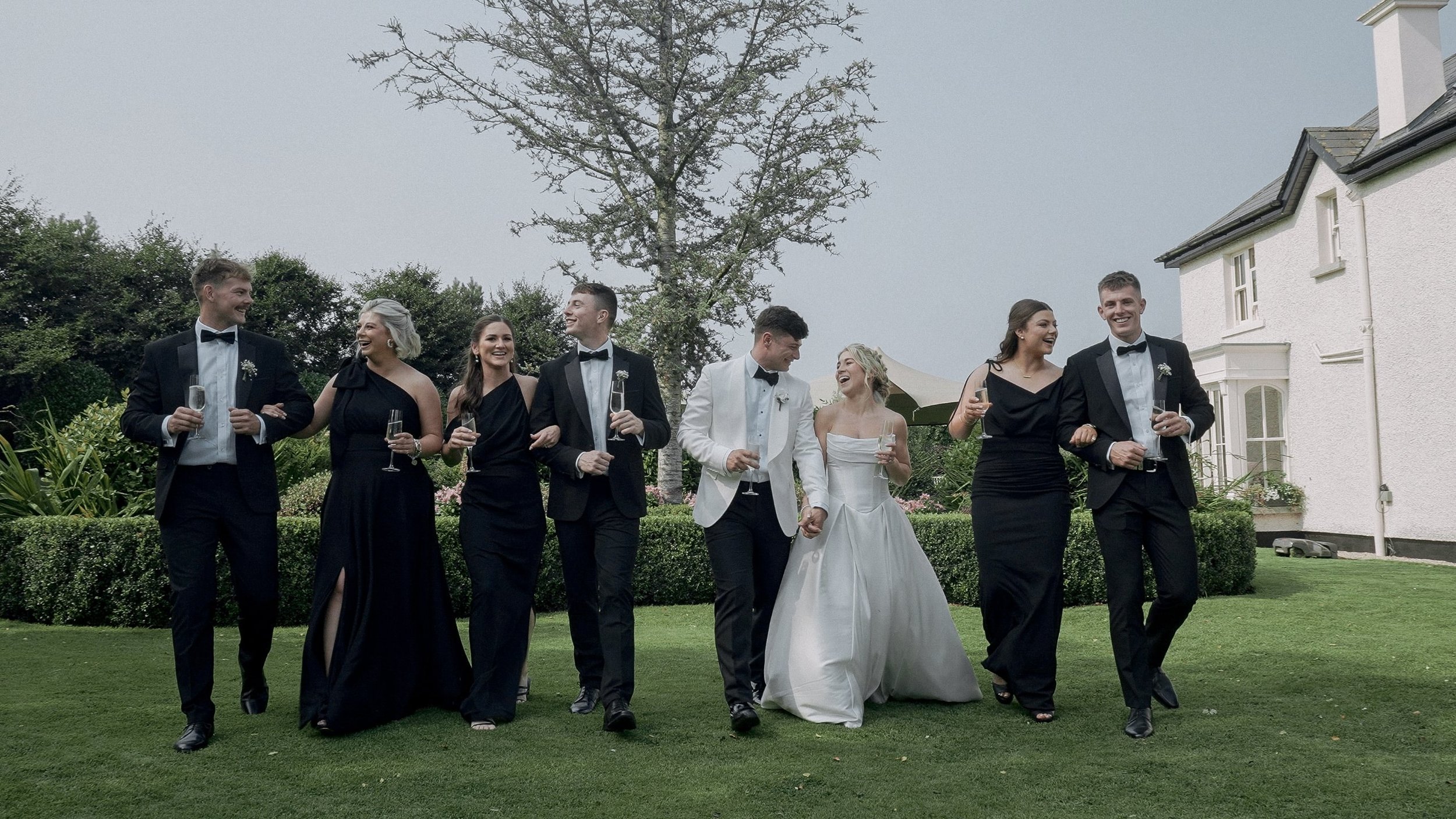 Bridal party walking across the lawn with champagne at a family home wedding on The Curragh
