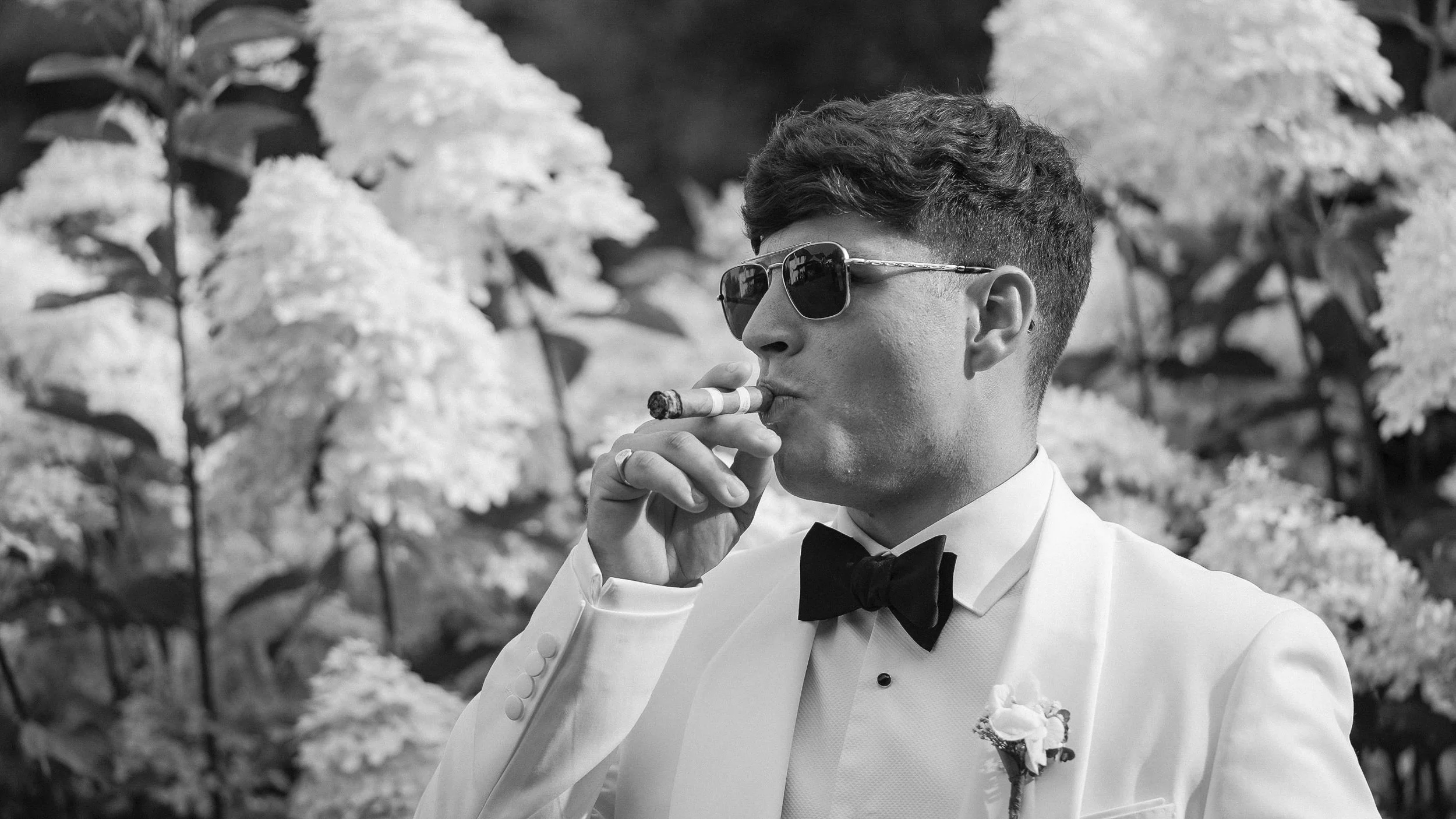 Groom in a white tuxedo jacket and sunglasses with a cigar, Curragh wedding in Kildare