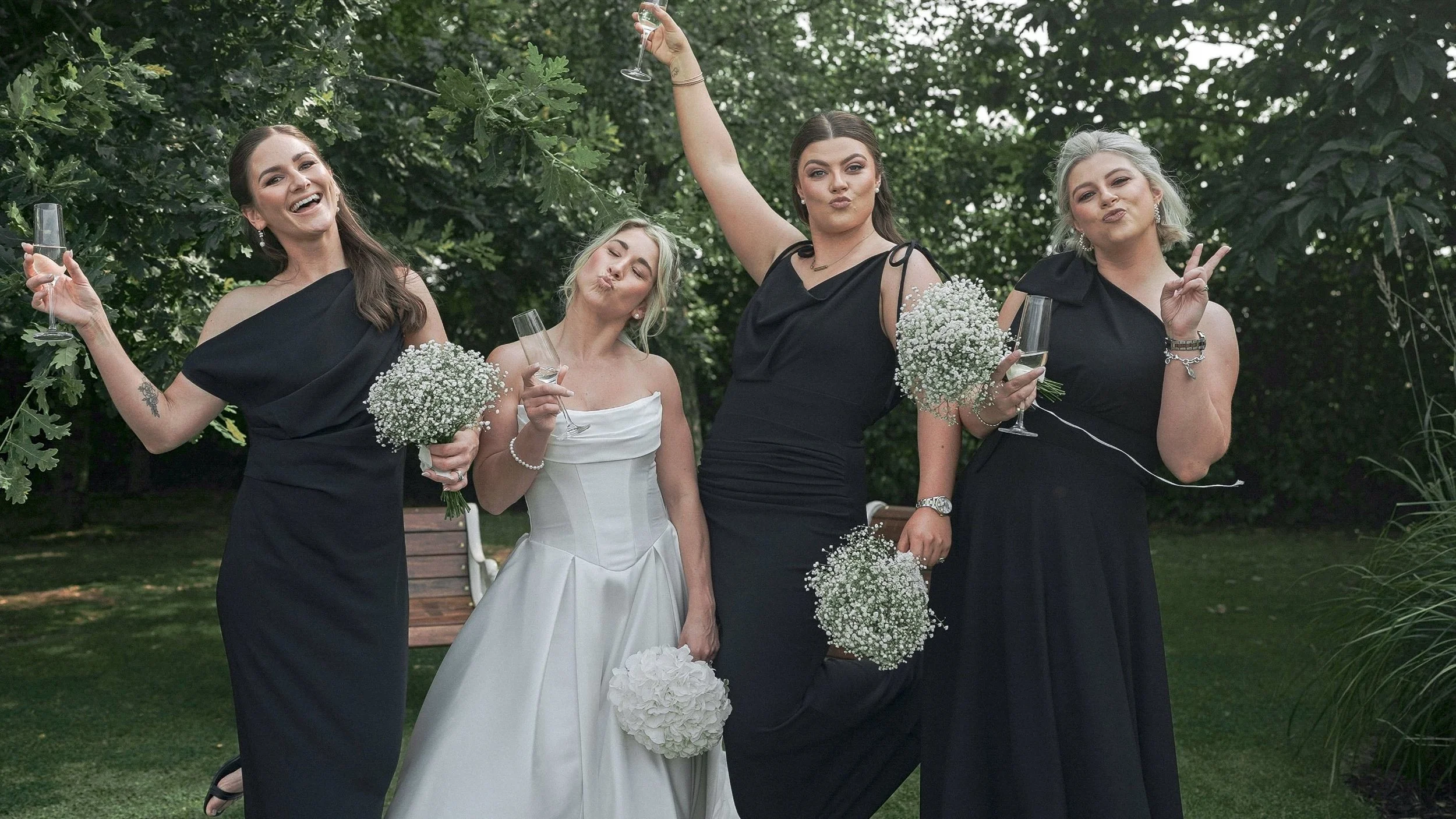 Bride and bridesmaids in black dresses with gypsophila bouquets having fun, Kildare wedding