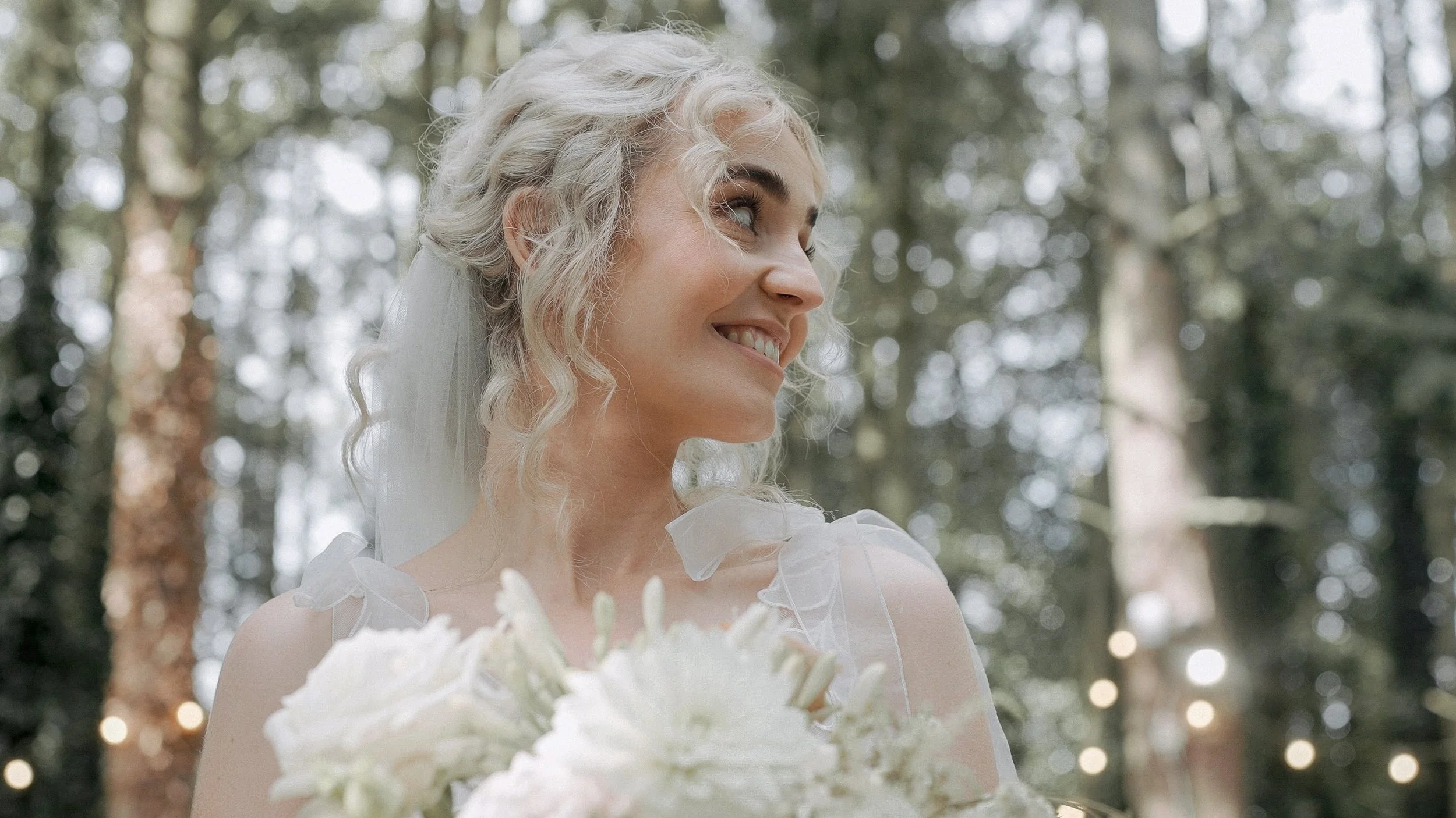 Bride smiling among the trees and festoon lights at the Station House Hotel, Kilmessan