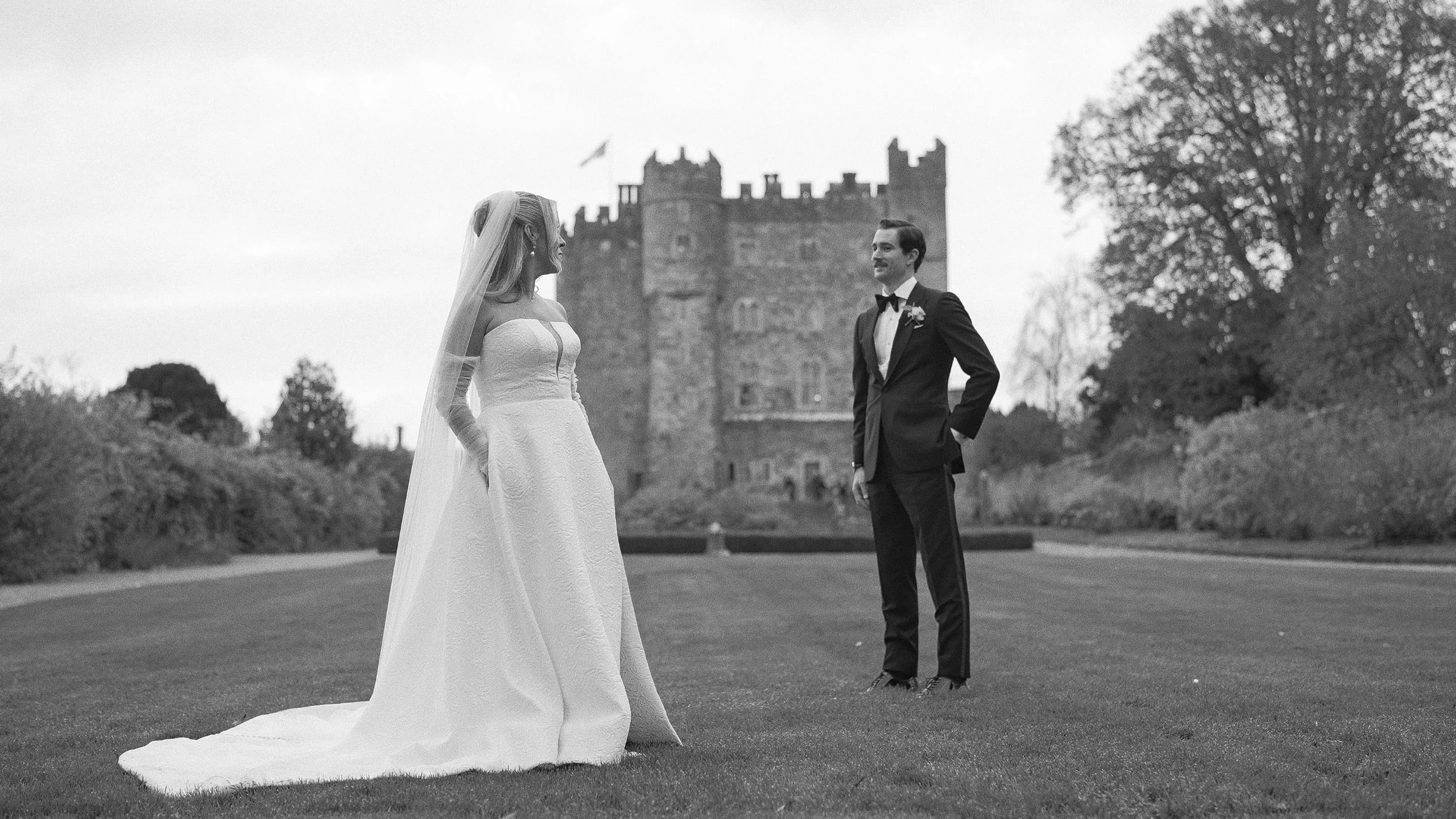Black and white photo of the couple on the lawn in front of Kilkea Castle, Castledermot