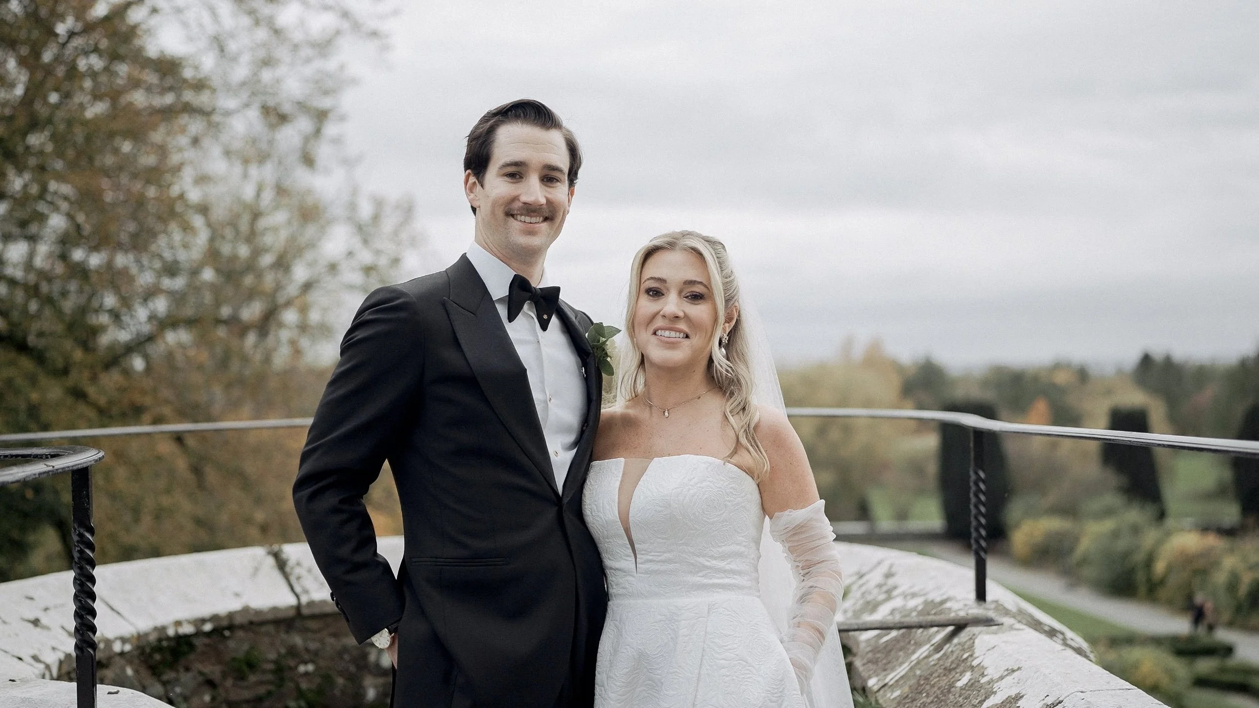 Smiling bride and groom on the castle terrace with autumn views over Kilkea, Co. Kildare