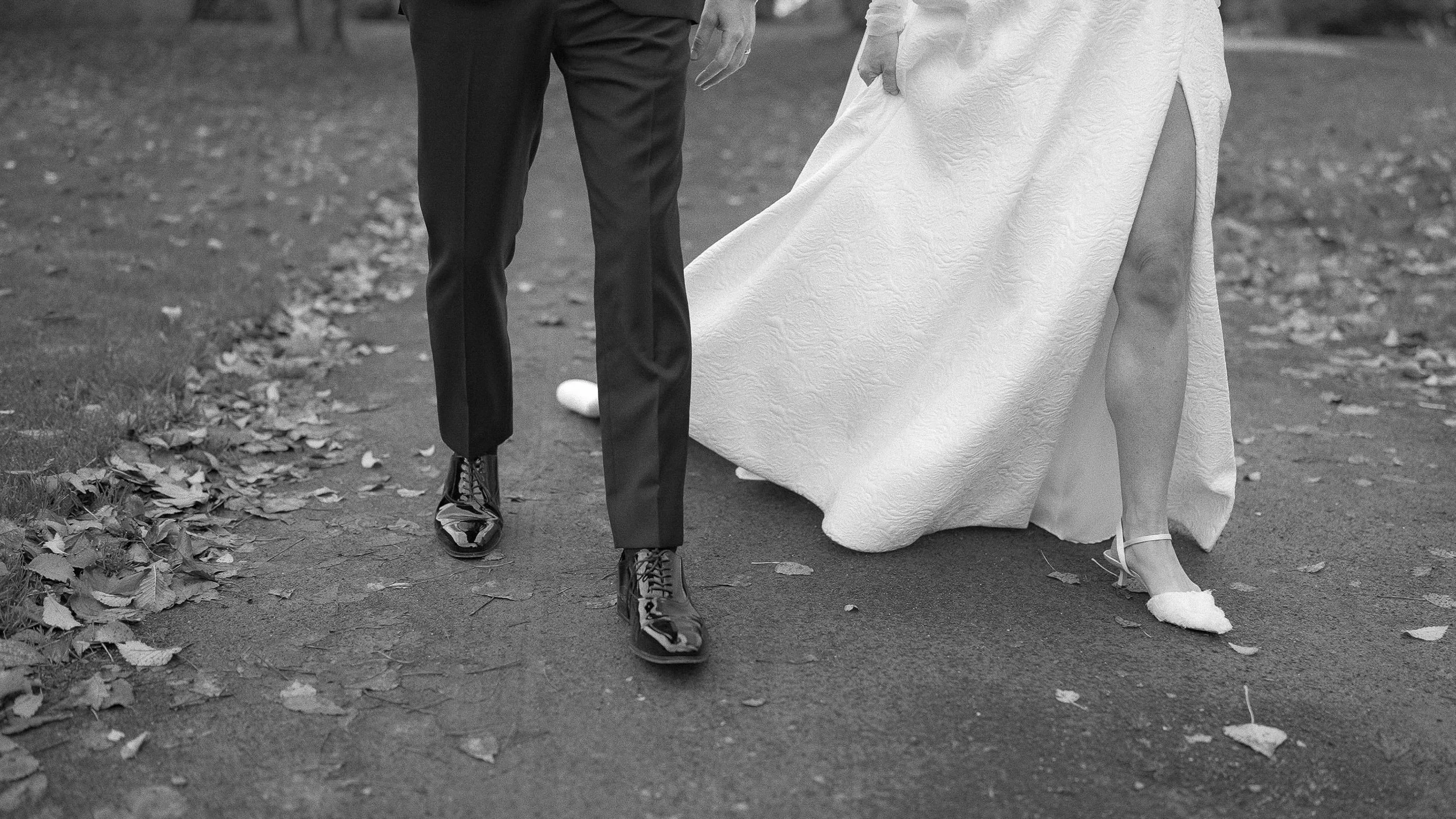 Black and white detail of the bride and groom walking on an autumn path at Kilkea Castle