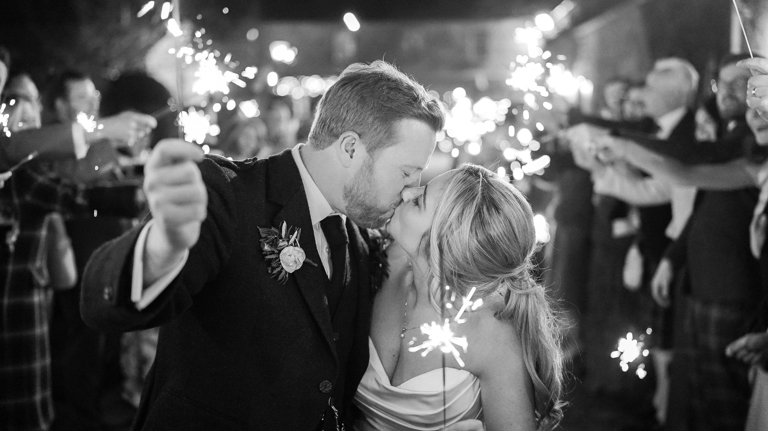 Black and white photo of a kiss during the sparkler send-off at Ballymagarvey Village wedding