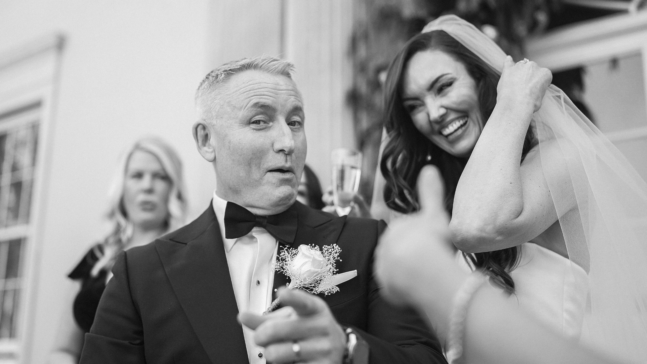 Black and white photo of the groom and laughing bride with guests at Clonwilliam House wedding