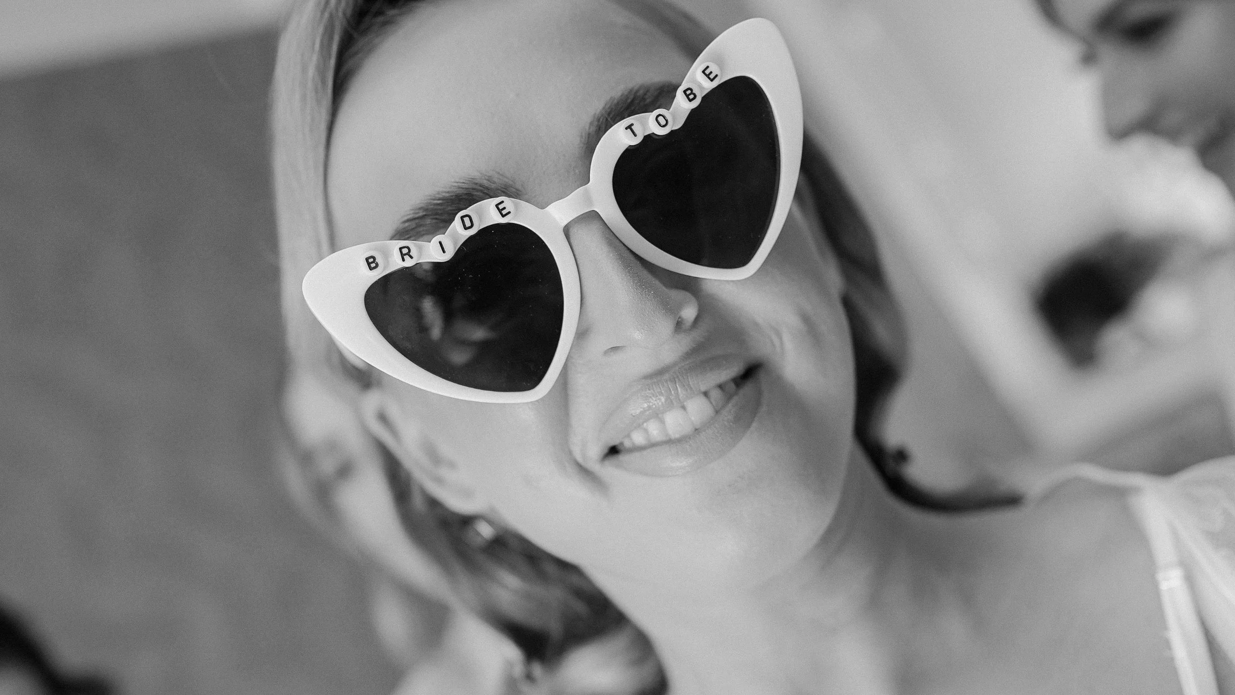 Smiling bride in heart-shaped Bride to be sunglasses on her wedding morning at Crover House Hotel, Co. Cavan