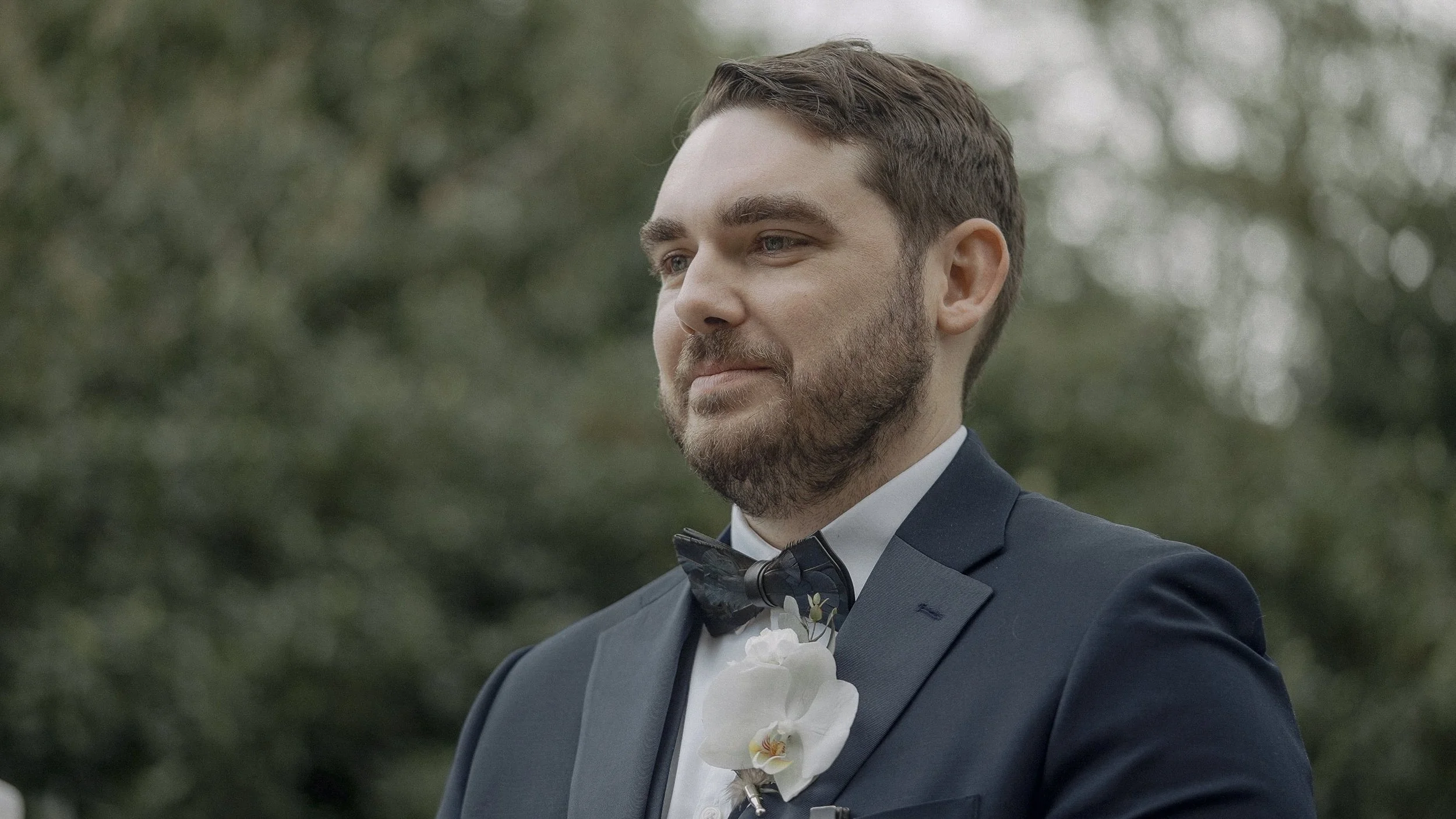 Groom with a white orchid buttonhole waiting for his bride at the outdoor ceremony at Waterford Castle