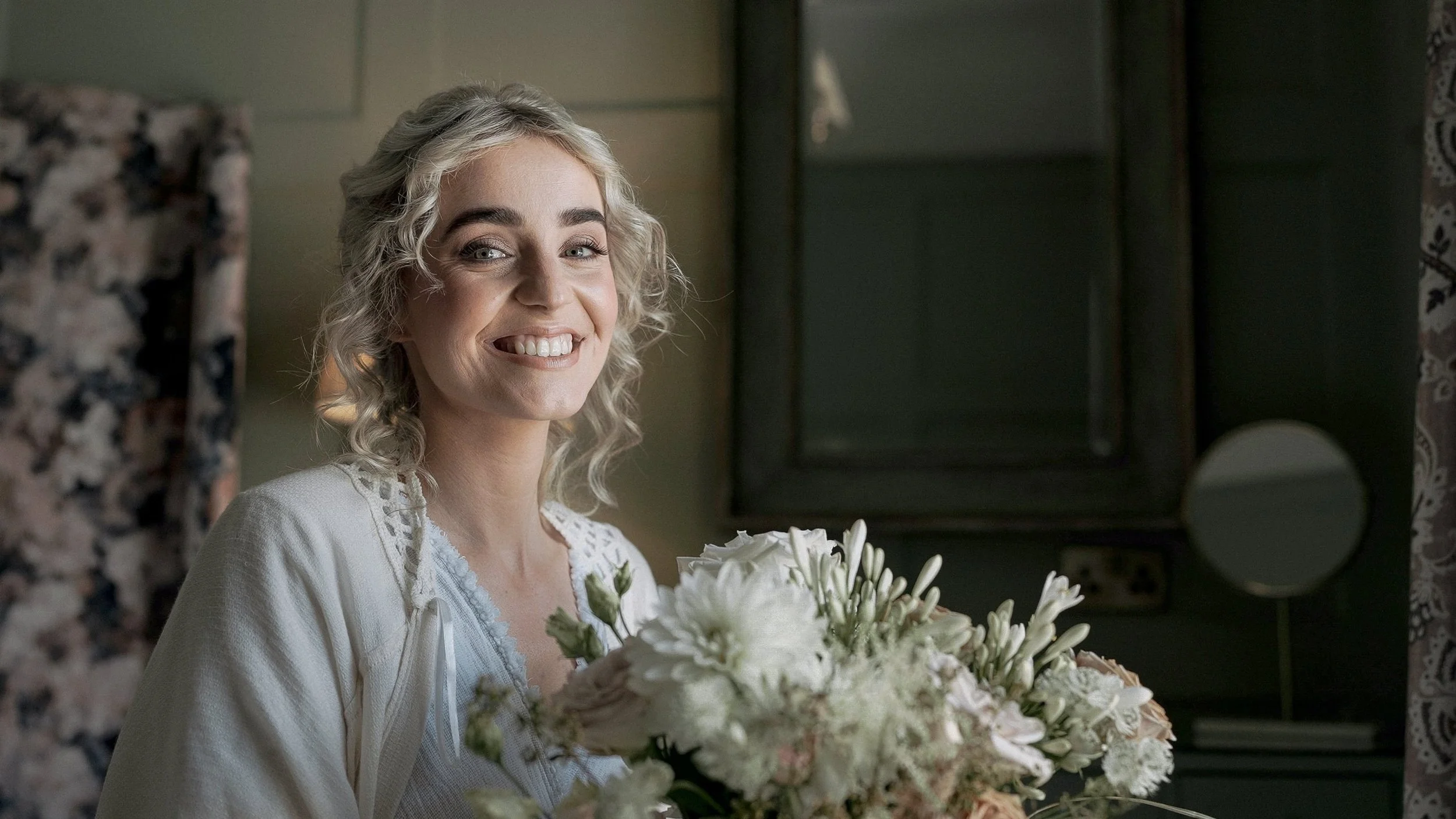 Smiling bride with vintage curls holding her bouquet while getting ready at the Station House Hotel, Meath